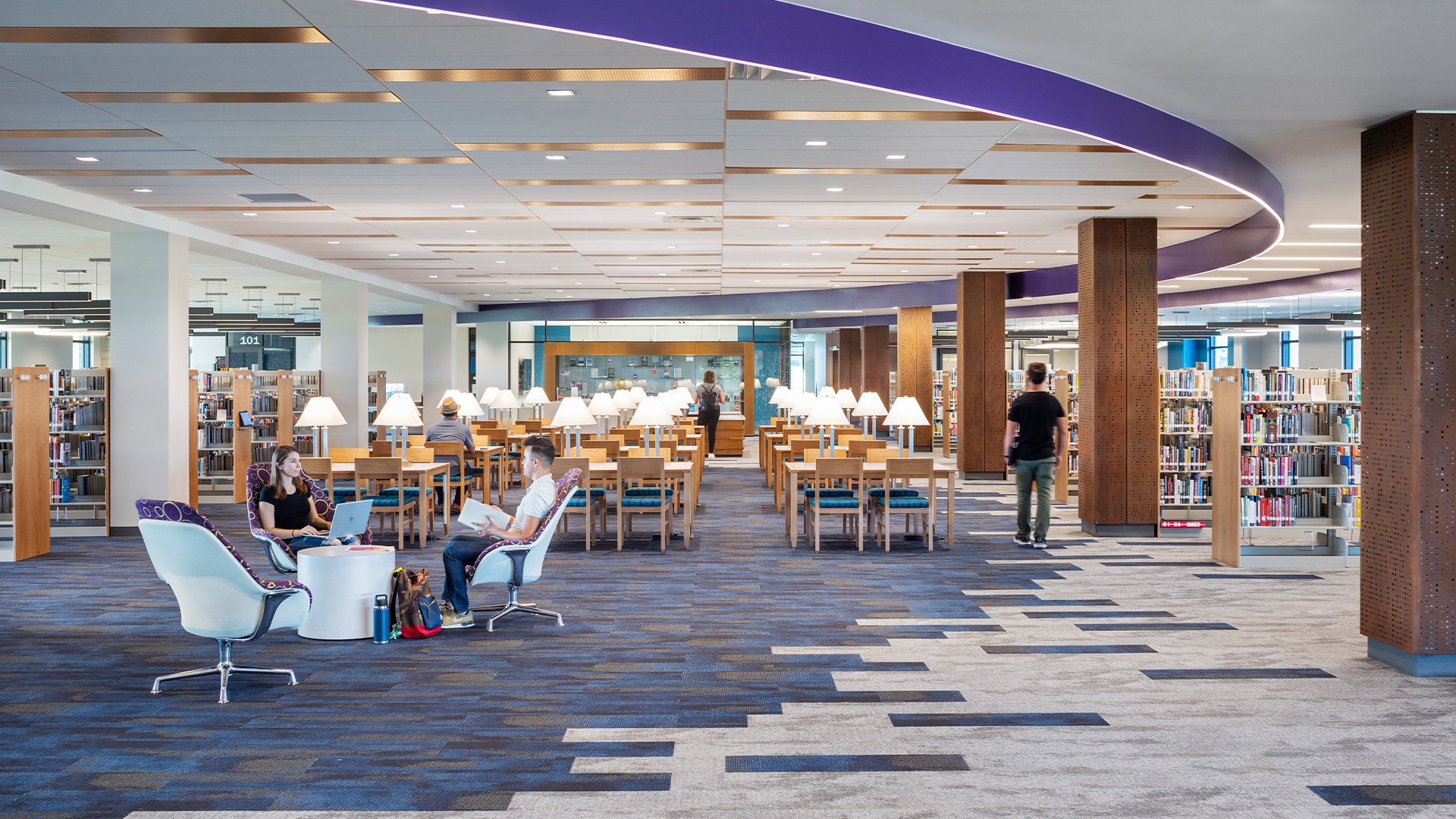 Education lab with Orange Chairs and Advanced Equipment Modern library interior with people studying, bookshelves, and stylish seating area.