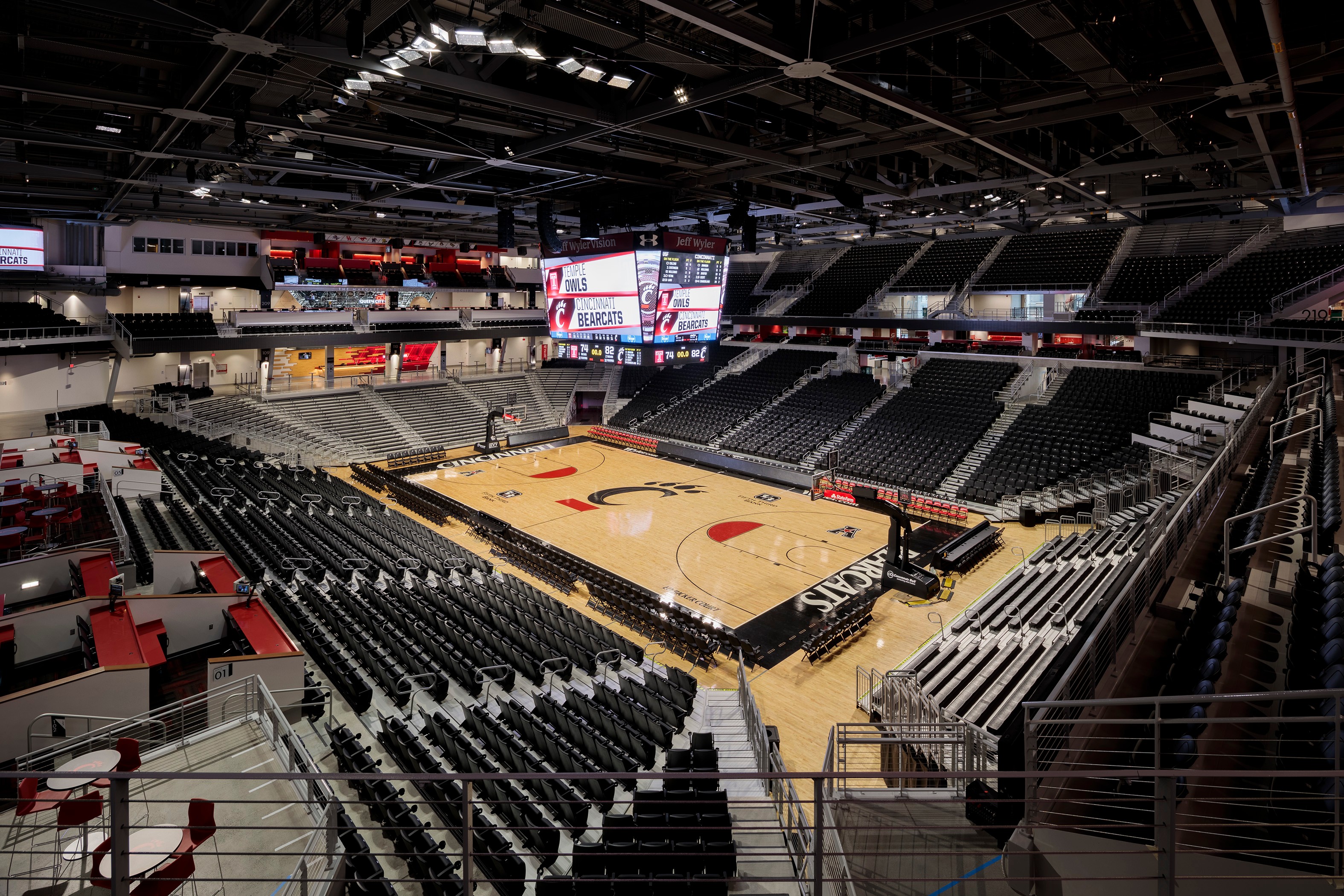 Interior view of an empty basketball arena with a wooden court and seating stands.