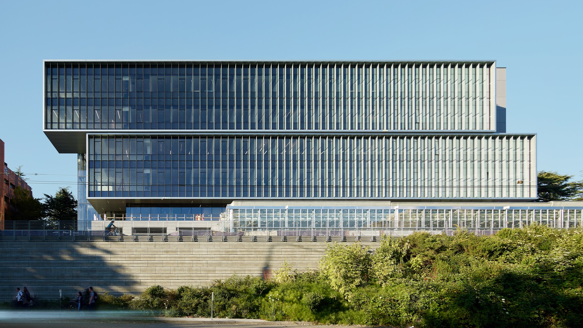 Education lab with Orange Chairs and Advanced Equipment Modern glass office building with tiered design and surrounding greenery under clear sky.