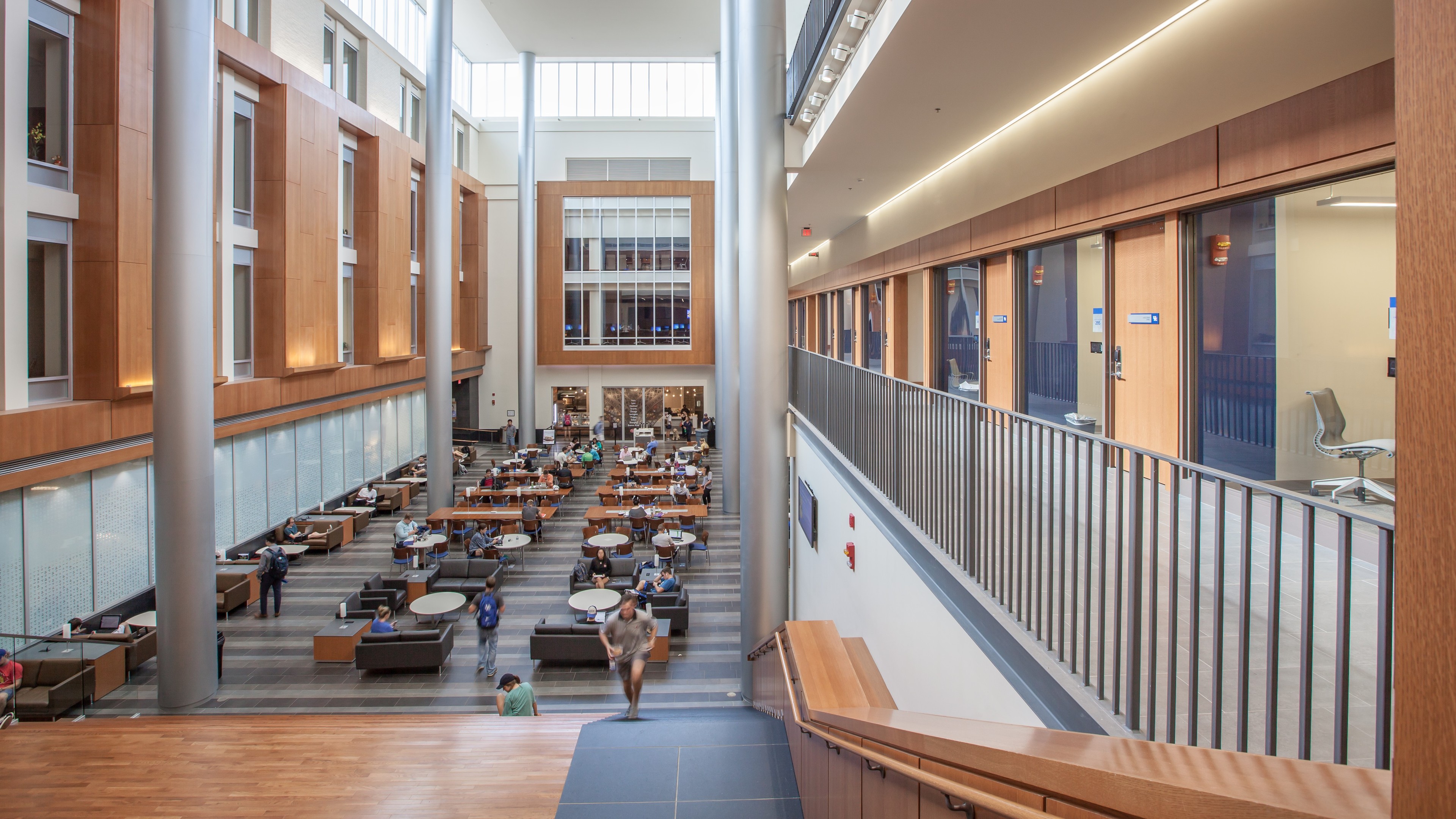 Education lab with Orange Chairs and Advanced Equipment Modern library interior with students studying at tables and natural light streaming in.