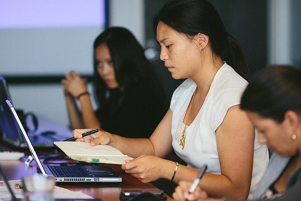 People working with laptops and notebooks in an office meeting setting.