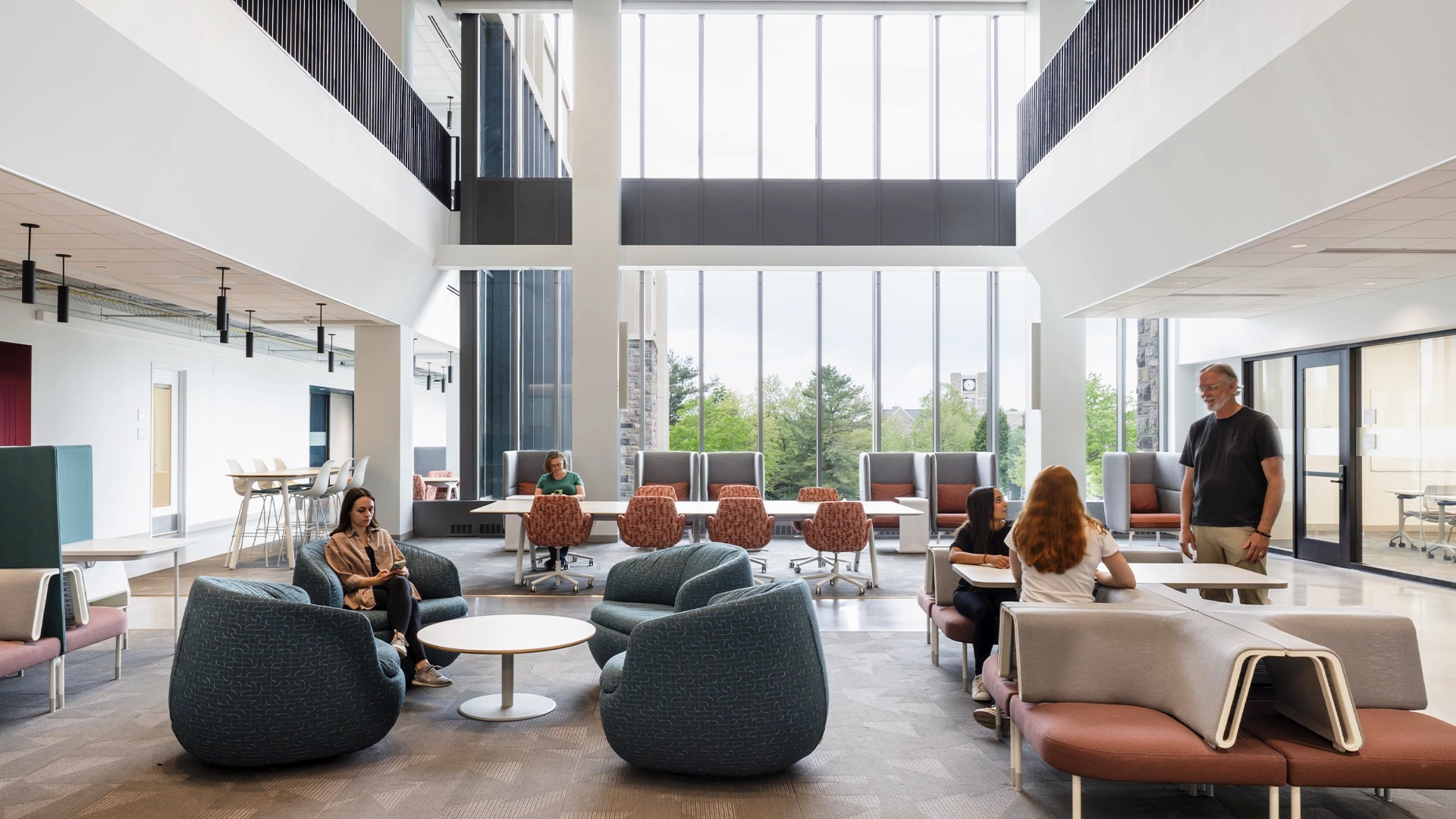Education lab with Orange Chairs and Advanced Equipment Modern office lounge with large windows, comfortable seating, and people collaborating.