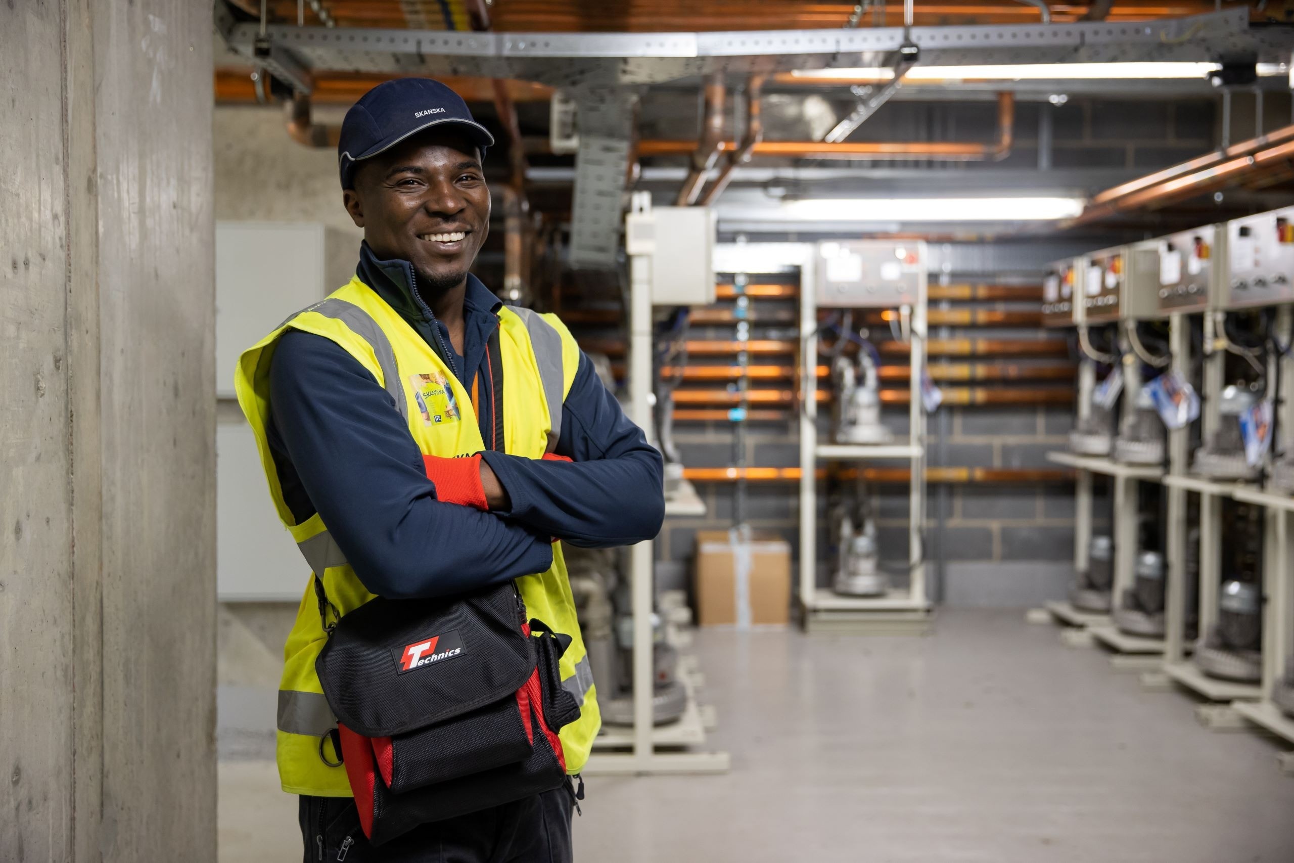 A Skanska colleague delivering FM support at a UK hospital A worker in a high-visibility vest stands in an industrial setting with electrical equipment