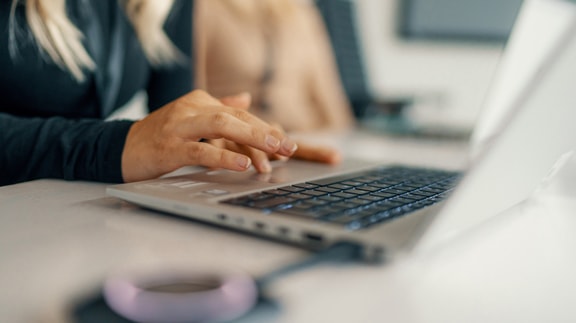 Person typing on a laptop keyboard, focusing on work in an office setting.