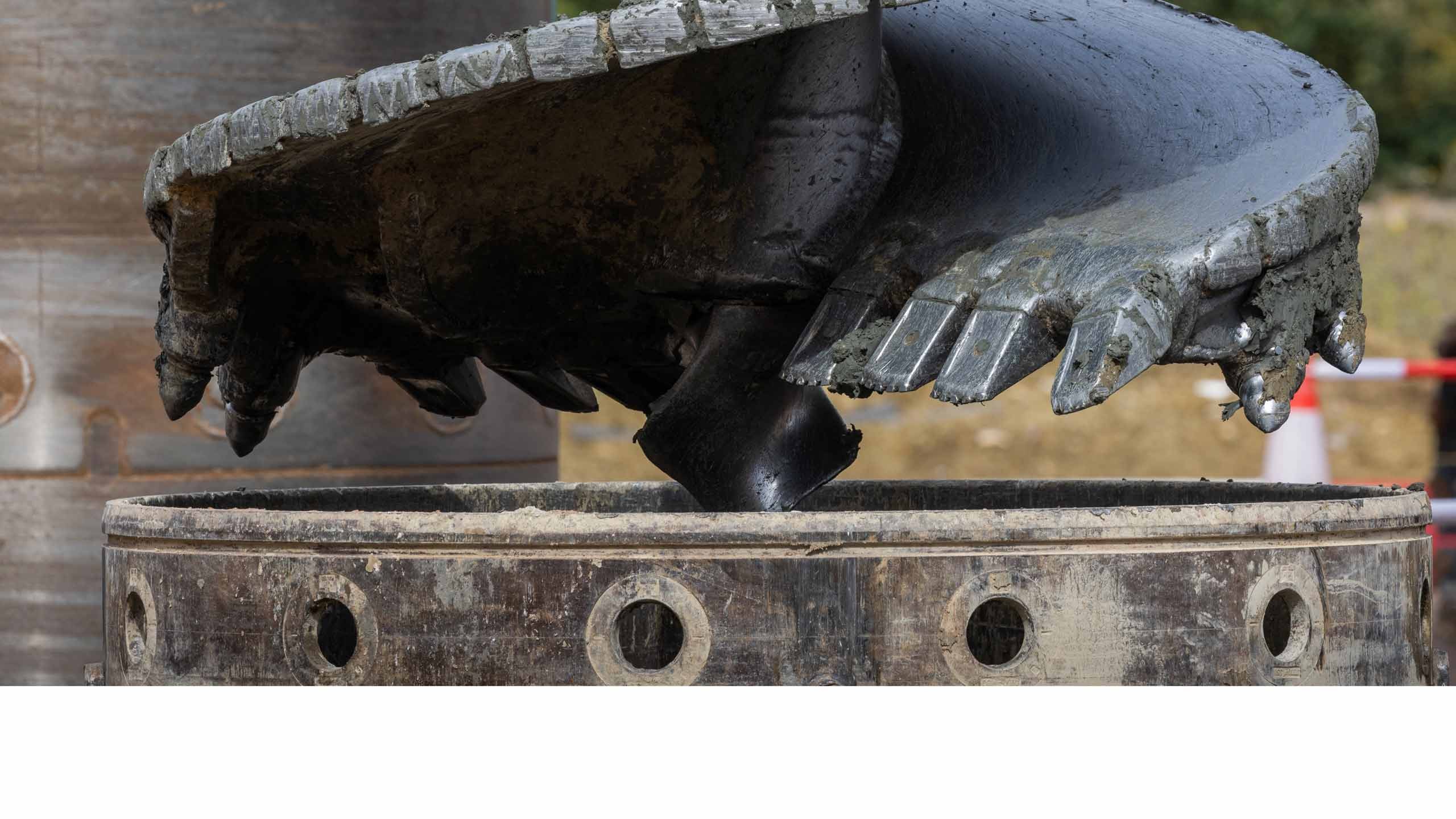 Close-up of a rotary drill bit, used for piling deep foundations up to 3m wide, and and the top of casing which stabilises the void. Close-up of a rotary drill bit, used for piling deep foundations up to 3m wide, and and the top of casing which stabilises the void.