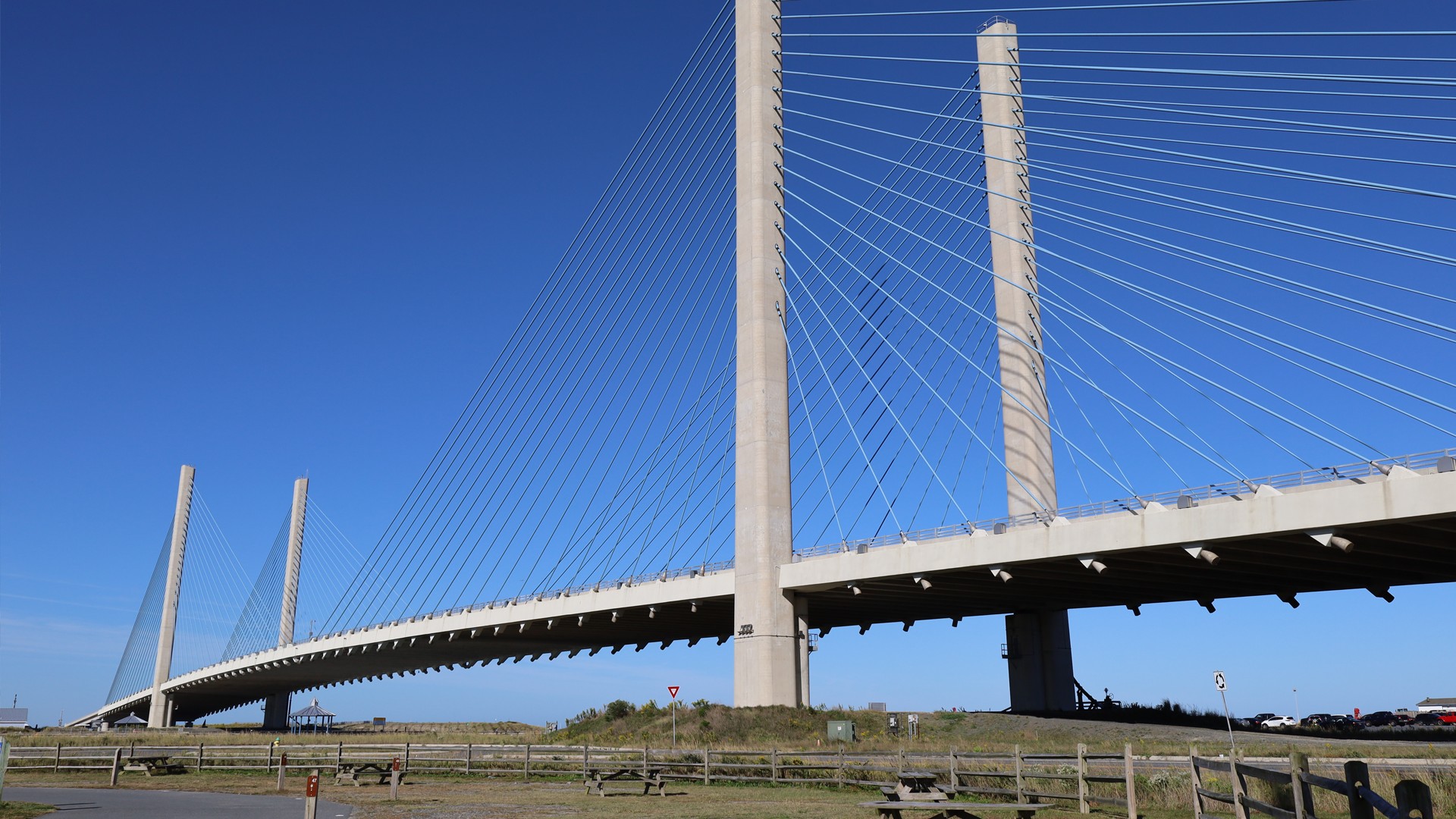 Modern Cable-Stayed Bridge Under Clear Blue Sky View Cable-stayed bridge with tall pylons against a clear blue sky and grassy surroundings.