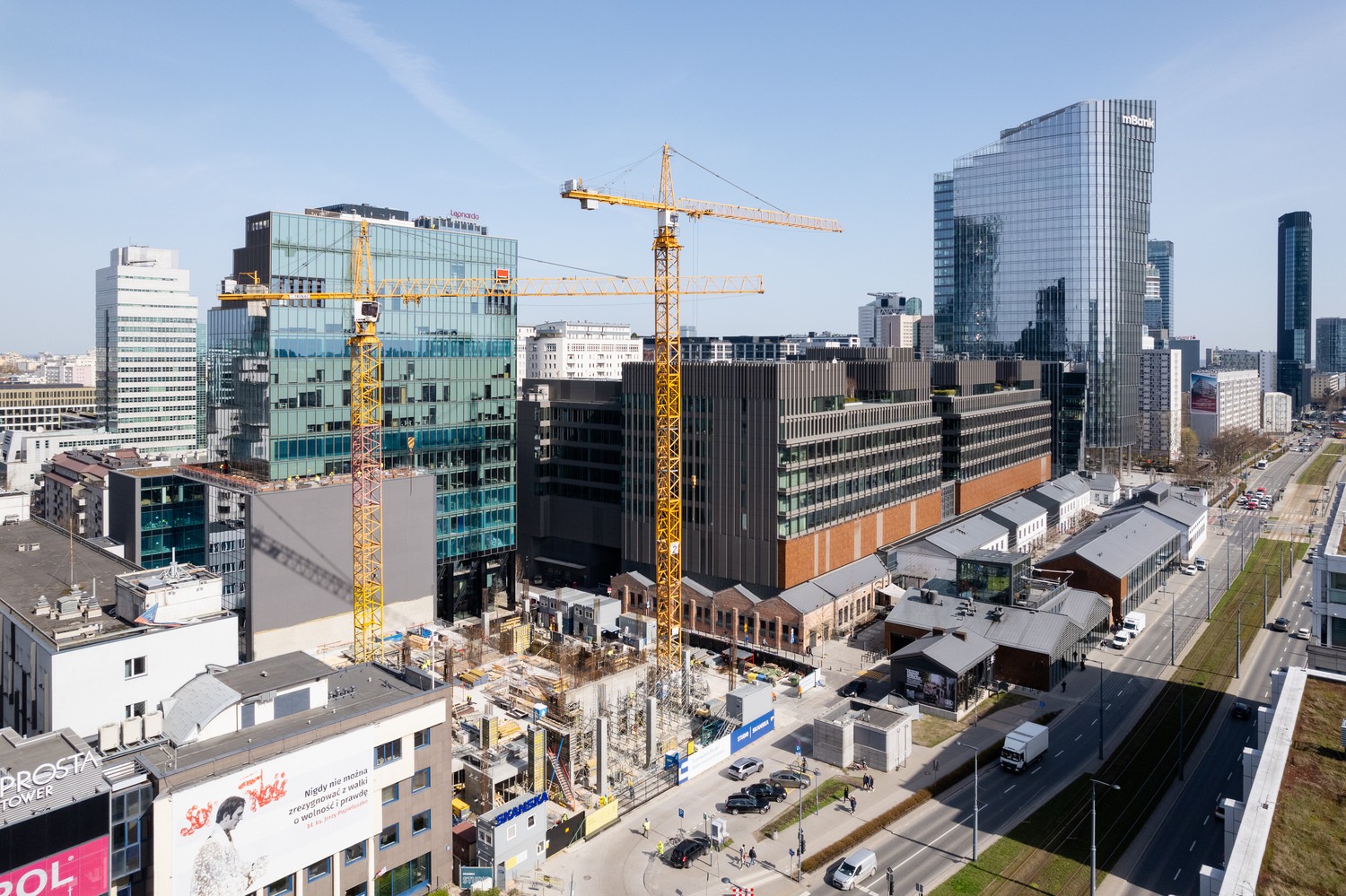 Urban Construction Scene with Modern Skyscrapers in Cityscape Miejska budowa z żurawiami, otoczona nowoczesnymi szklanymi drapaczami chmur i ruchliwymi ulicami.
