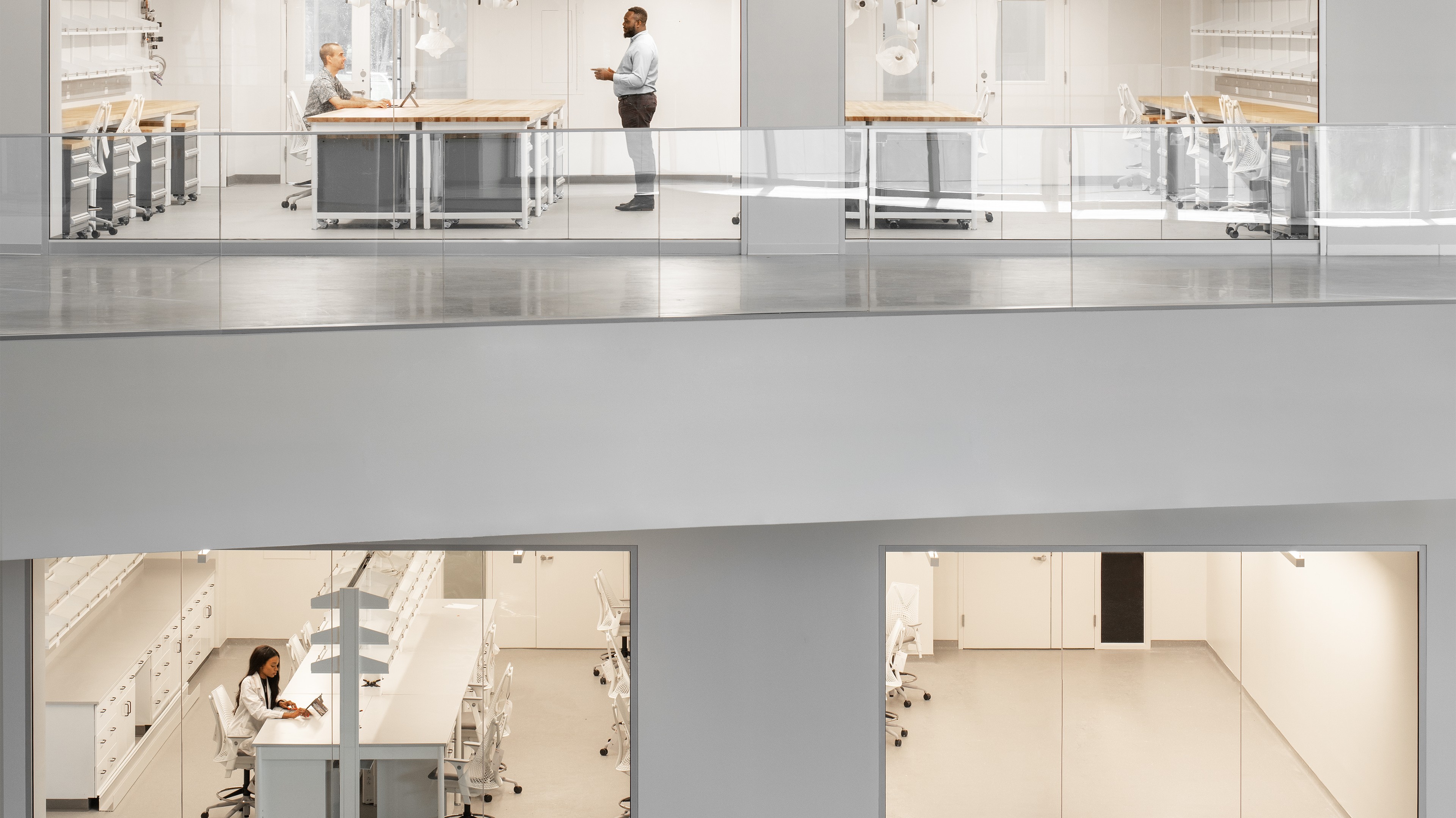 Education lab with Orange Chairs and Advanced Equipment Modern office interior with professionals working at desks in a bright, minimalist space.