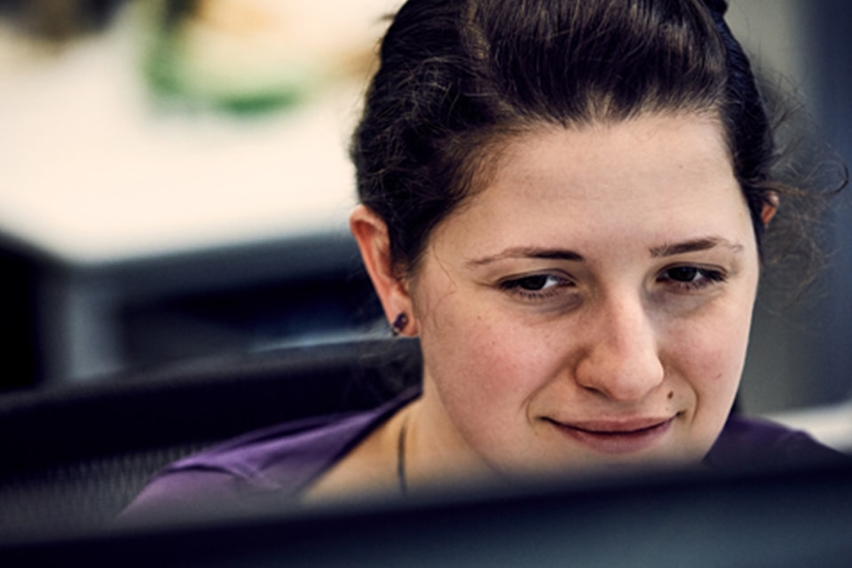 Woman working at computer in office setting with blurred background.
