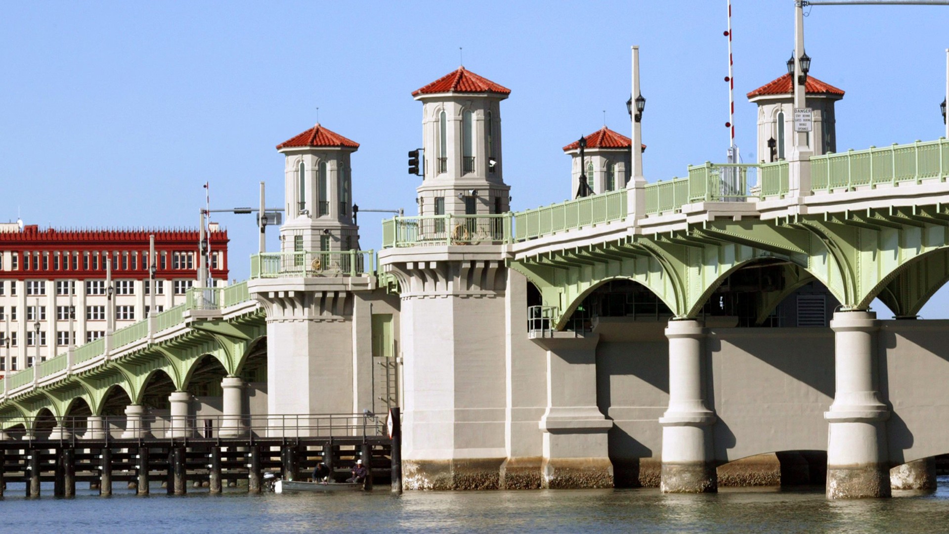 Historic drawbridge with towers over calm river on clear day Historic Bridge of Lions drawbridge with towers and arches over calm water under clear blue sky.