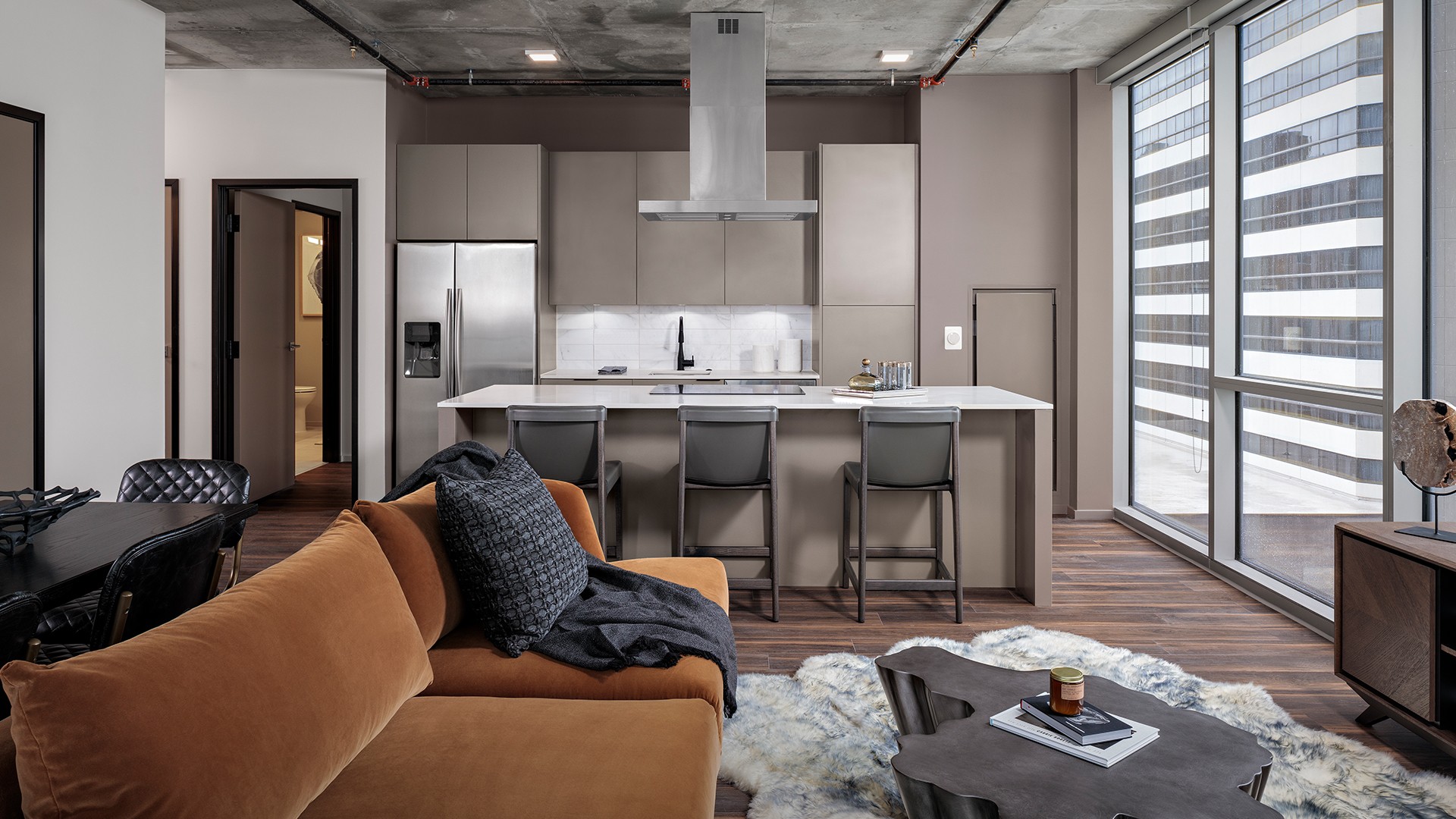 Modern apartment interior with open kitchen, stylish seating, and large windows.