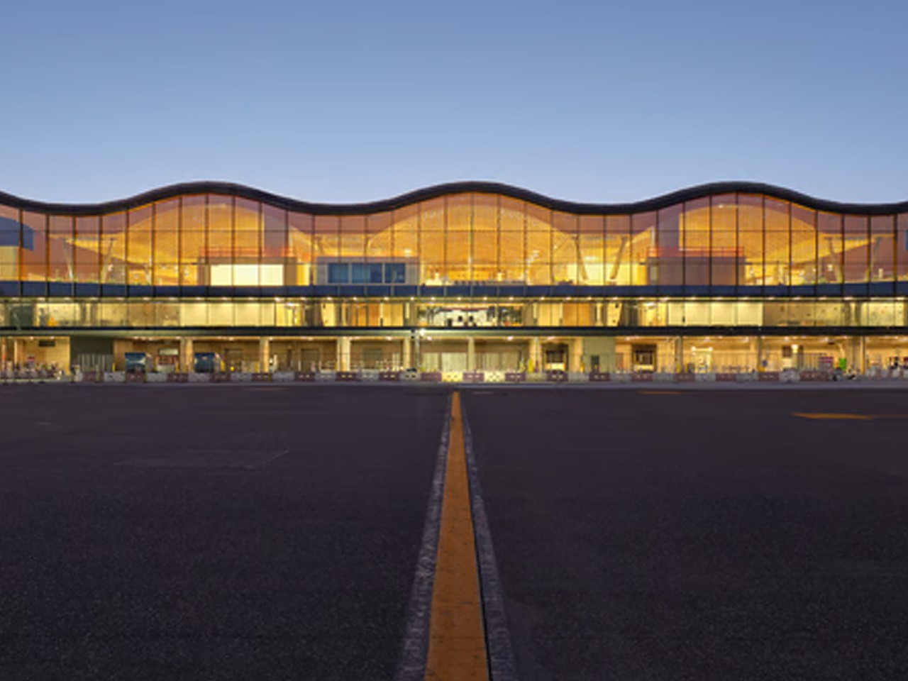 PDX Airport Terminal with Curved Glass Facade at Sunset PDX airport terminal with large glass windows and a clear sky at dusk.