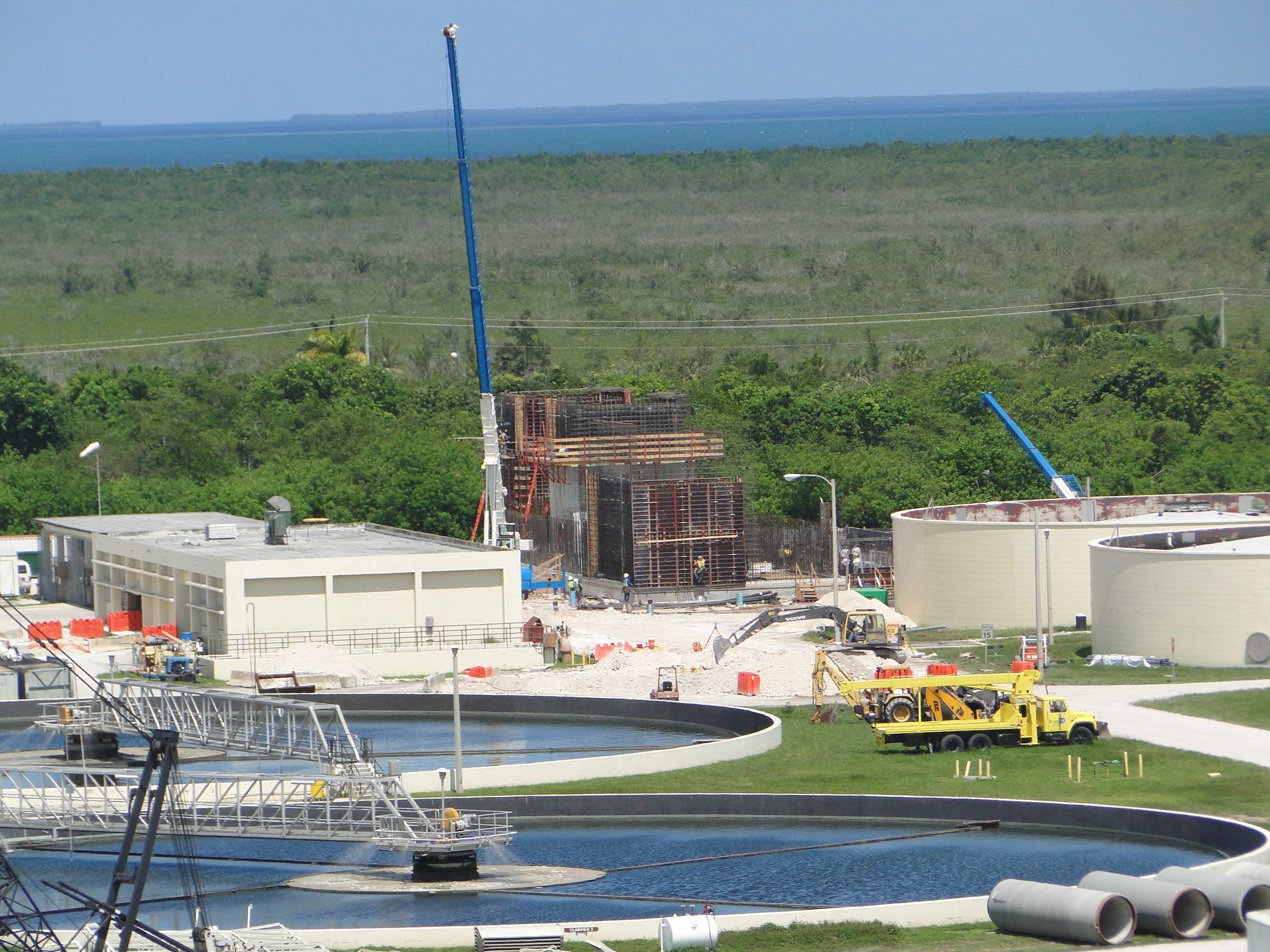 Water Treatment Plant Construction Site with Storage Tanks Water treatment facility with large tanks, cranes, and industrial buildings near water.