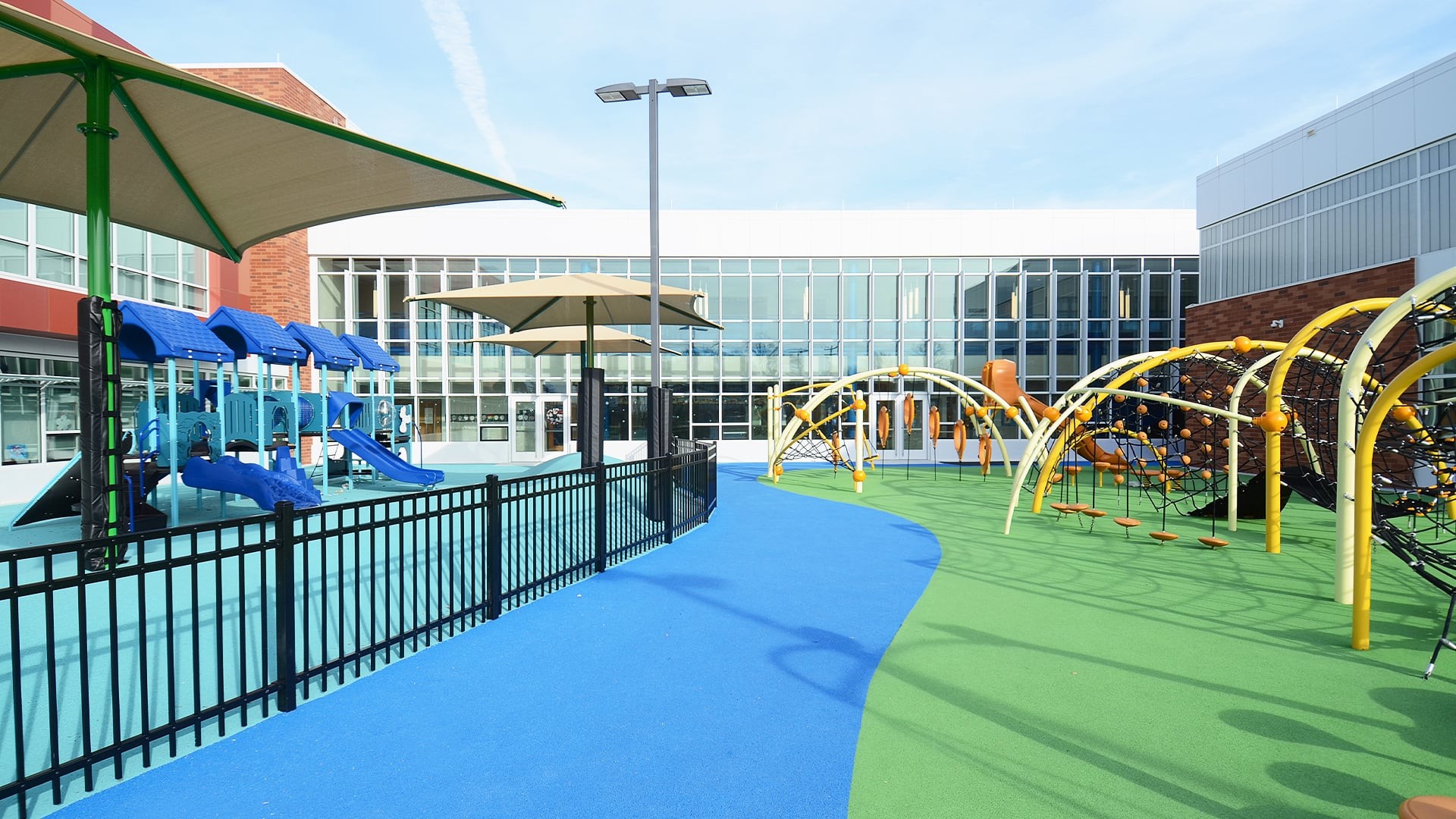 School Library Interior with Wooden Ceiling and Bookshelves Outdoor school playground with slides, climbing structures, and colorful rubber flooring.