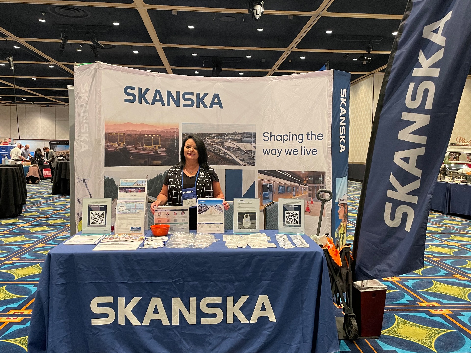 Skanska Exhibition Booth at Industry Conference with Staff Skanska trade show booth with representative, promotional materials, and branded display.