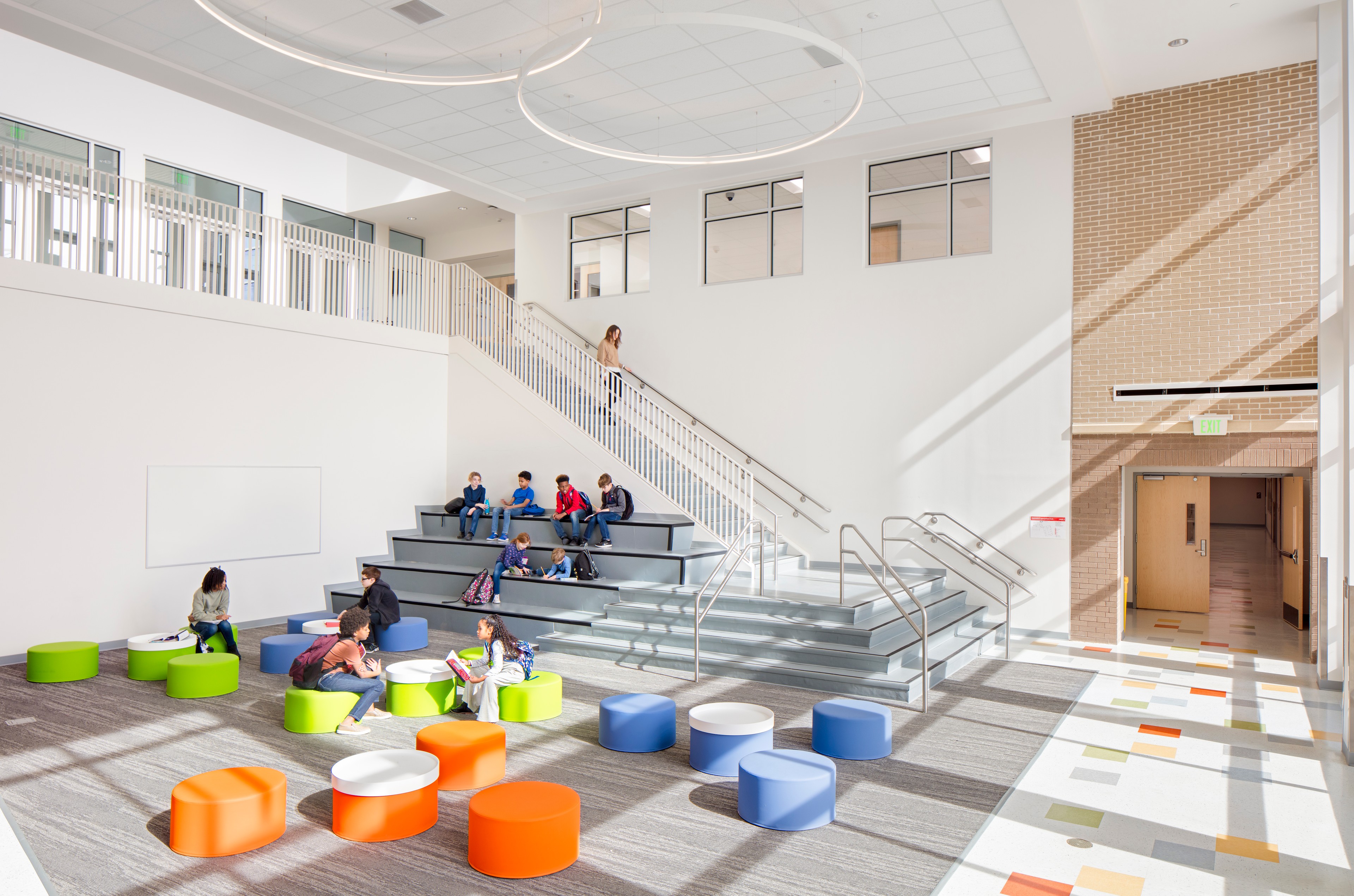 Modern school common area with colorful seating, tiered steps, and natural light.