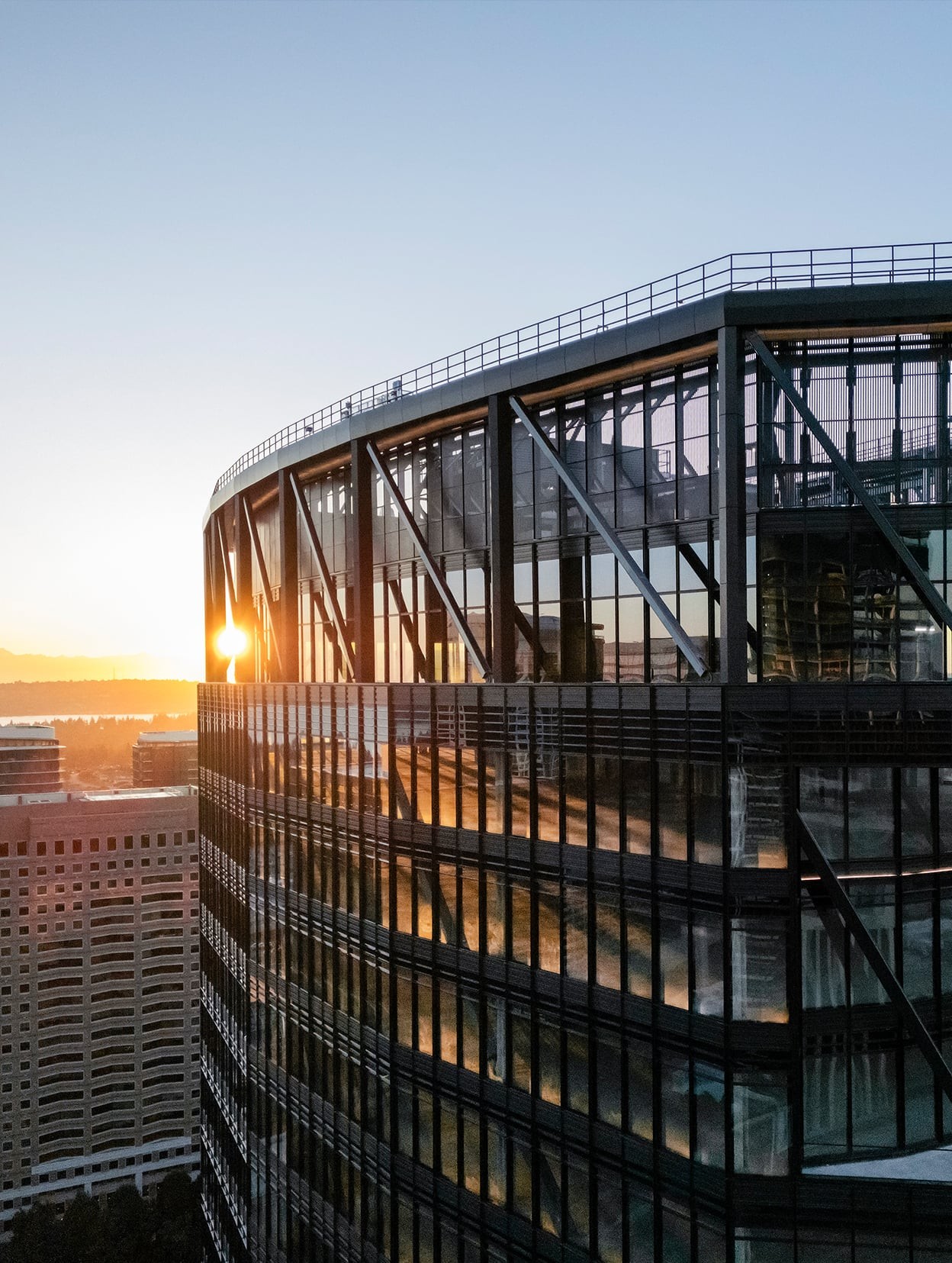 Modern glass office building at sunset with sunlight reflecting on windows.