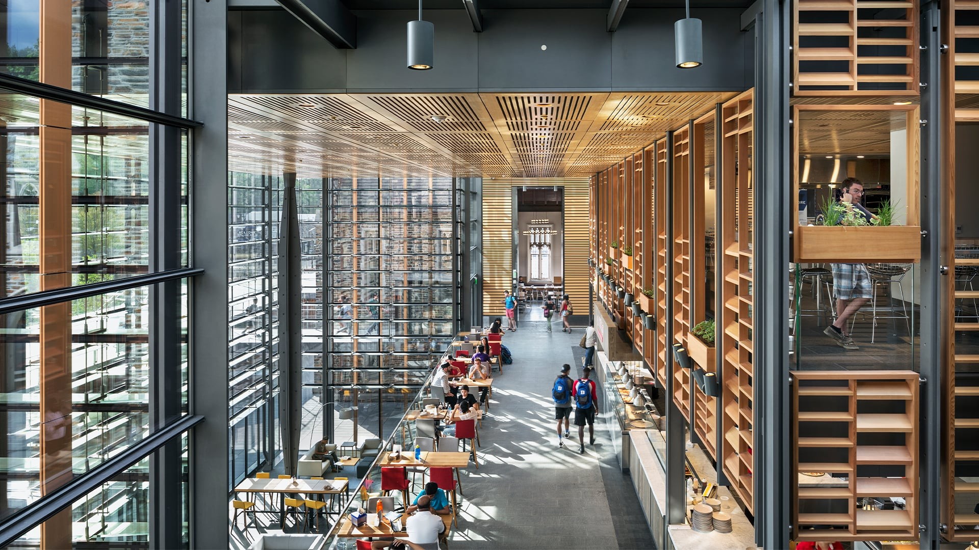 Education lab with Orange Chairs and Advanced Equipment Modern library interior with large windows, wooden shelves, and people studying.