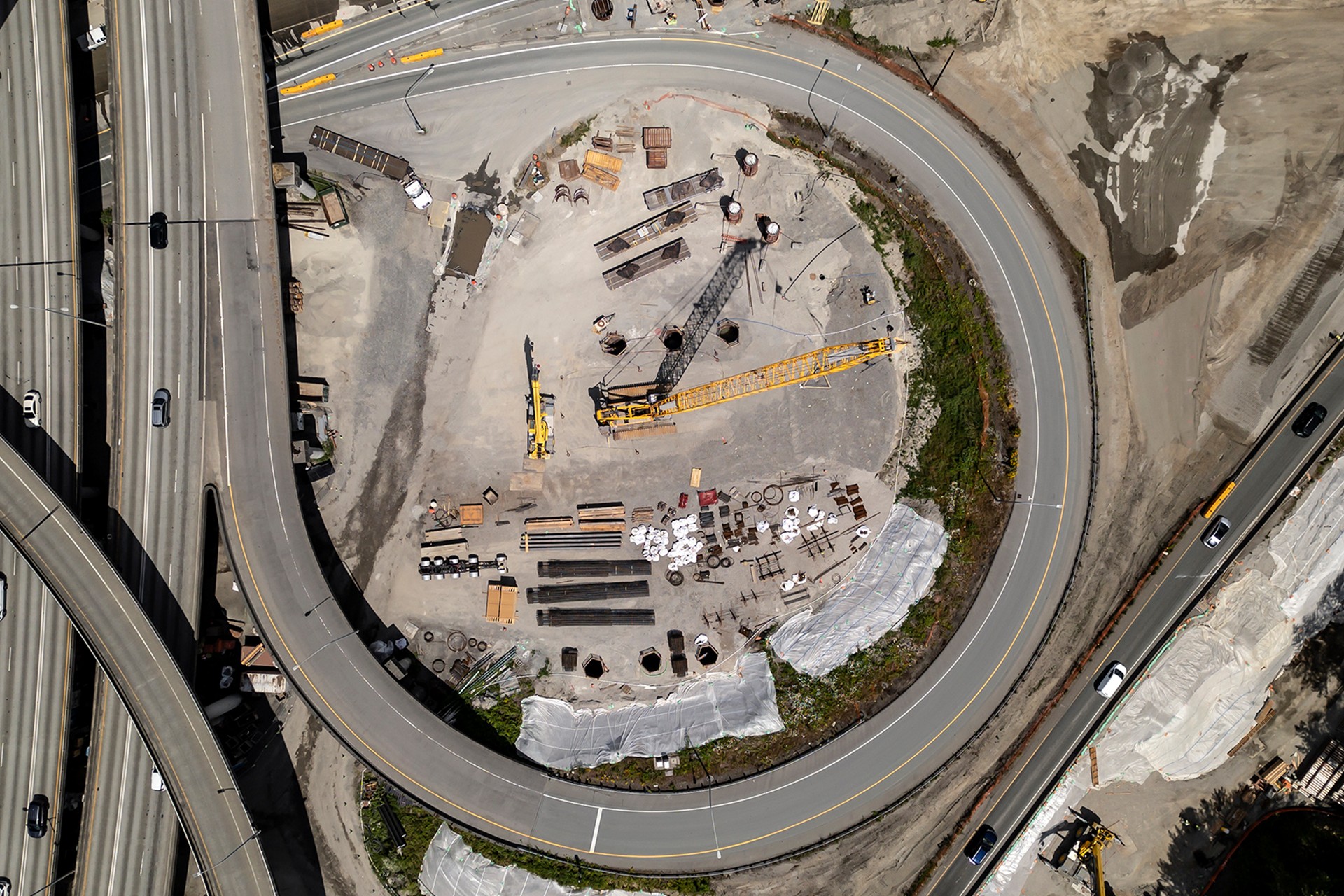 Aerial View of Circular Road Construction Site with Cranes Aerial view of a circular construction site surrounded by curved roads and vehicles.
