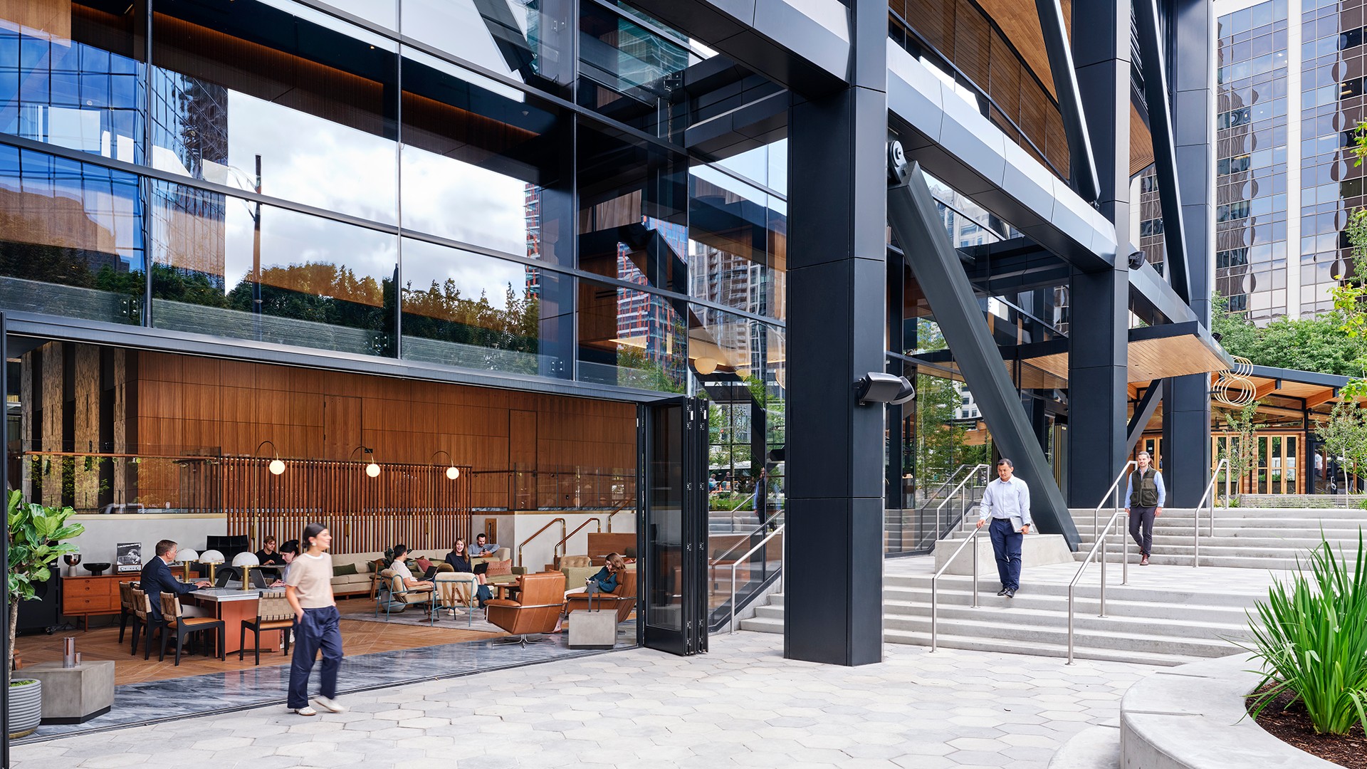Modern Office Building with Outdoor Seating and Glass Facade Modern office building with glass facade, outdoor seating, and people walking nearby.