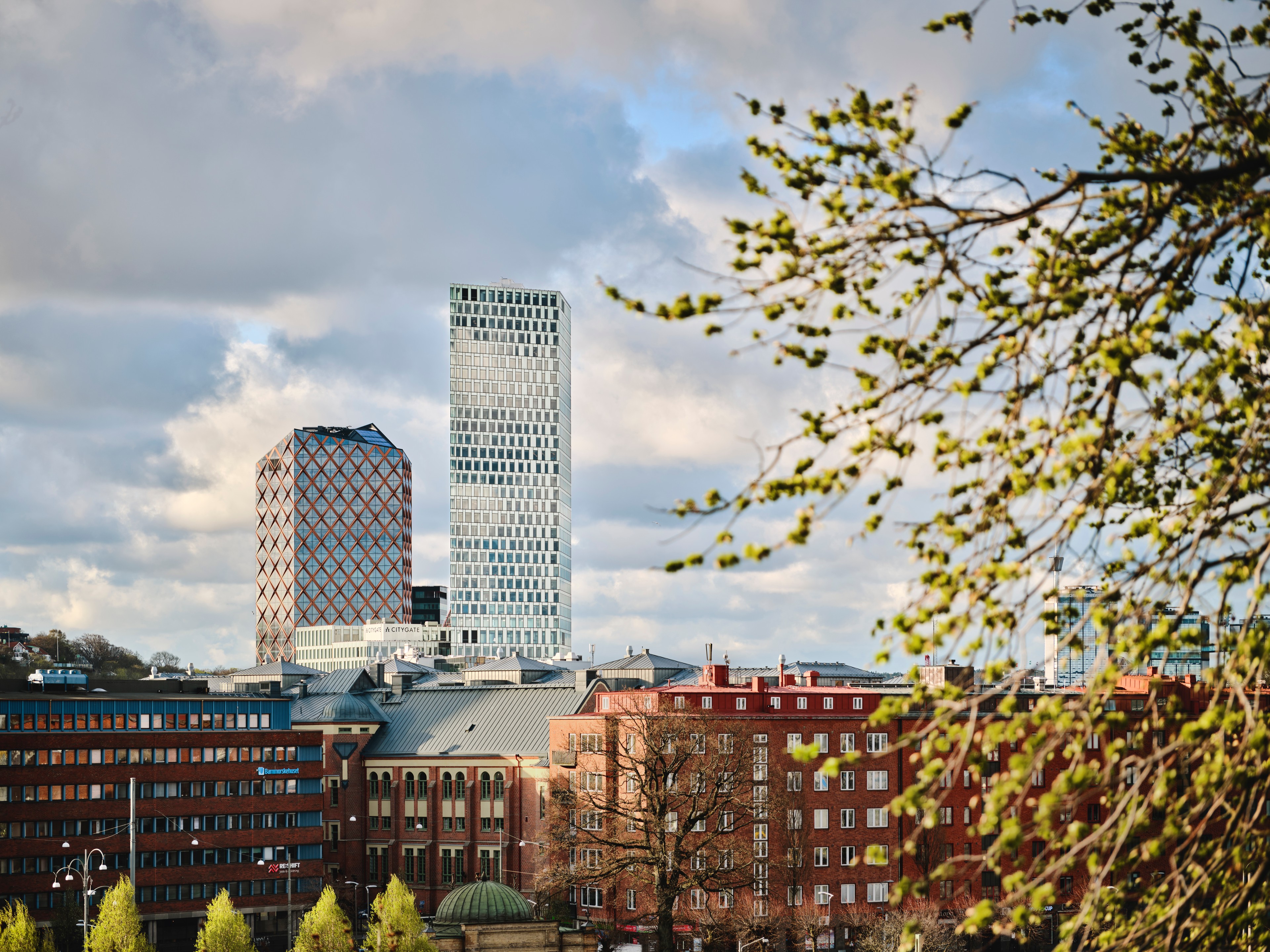 Modern Office Tower in Vibrant Urban Business District Modern high-rise building in urban setting under blue sky, featuring glass facade and surrounding roads.