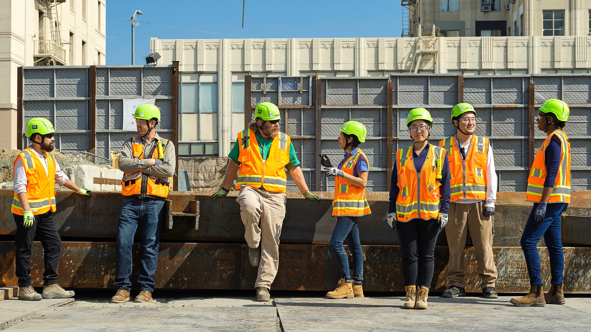Construction workers in safety gear at urban site meeting Construction workers in safety gear standing and talking on an urban building site.