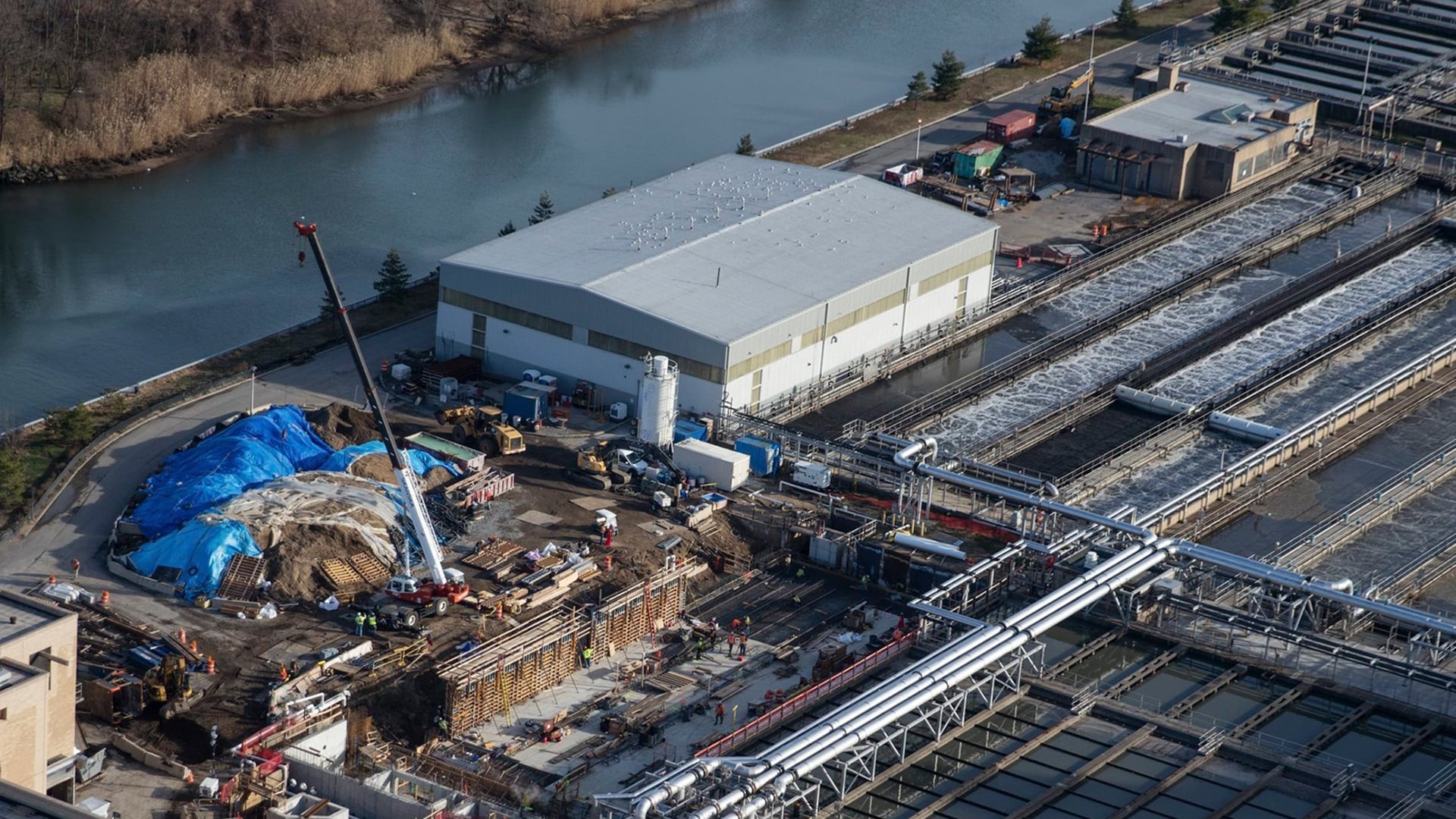 Aerial view of an industrial water treatment plant under construction by a river.