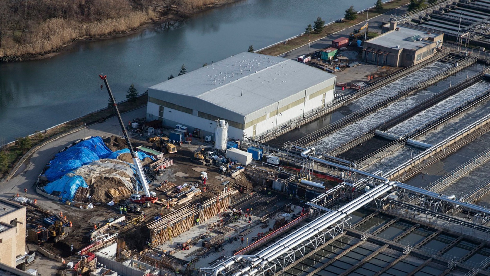 Water Treatment Plant Construction Site by River in Clear Day Aerial view of an industrial water treatment plant under construction by a river.