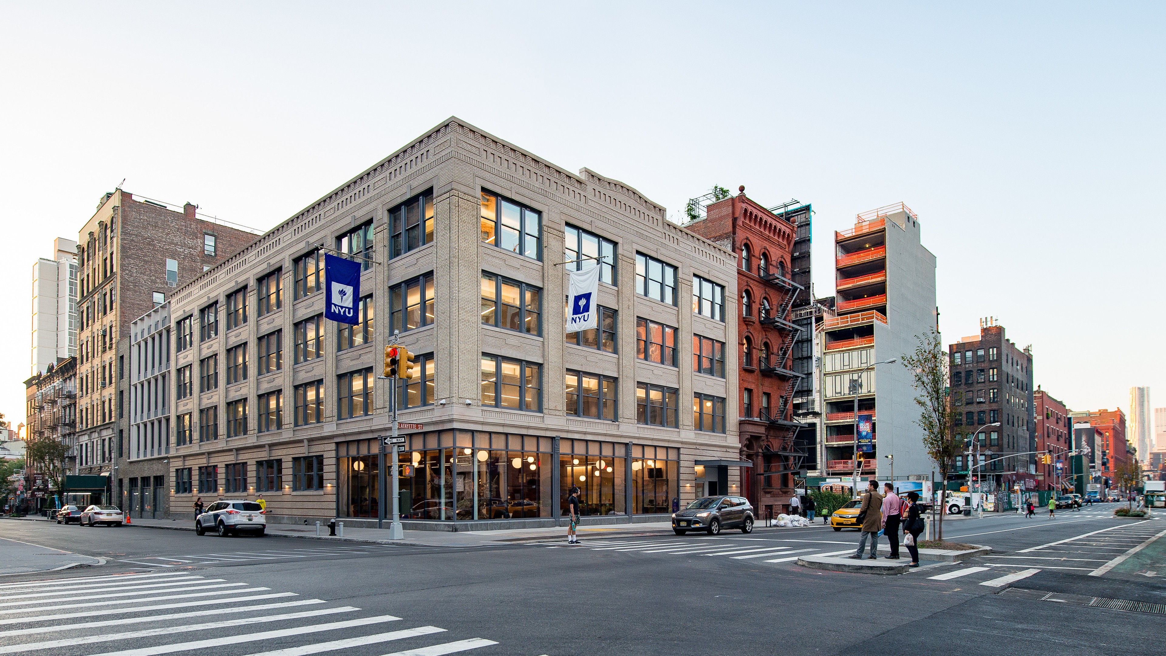 Education lab with Orange Chairs and Advanced Equipment Urban street corner with a large NYU building and pedestrians crossing the road.