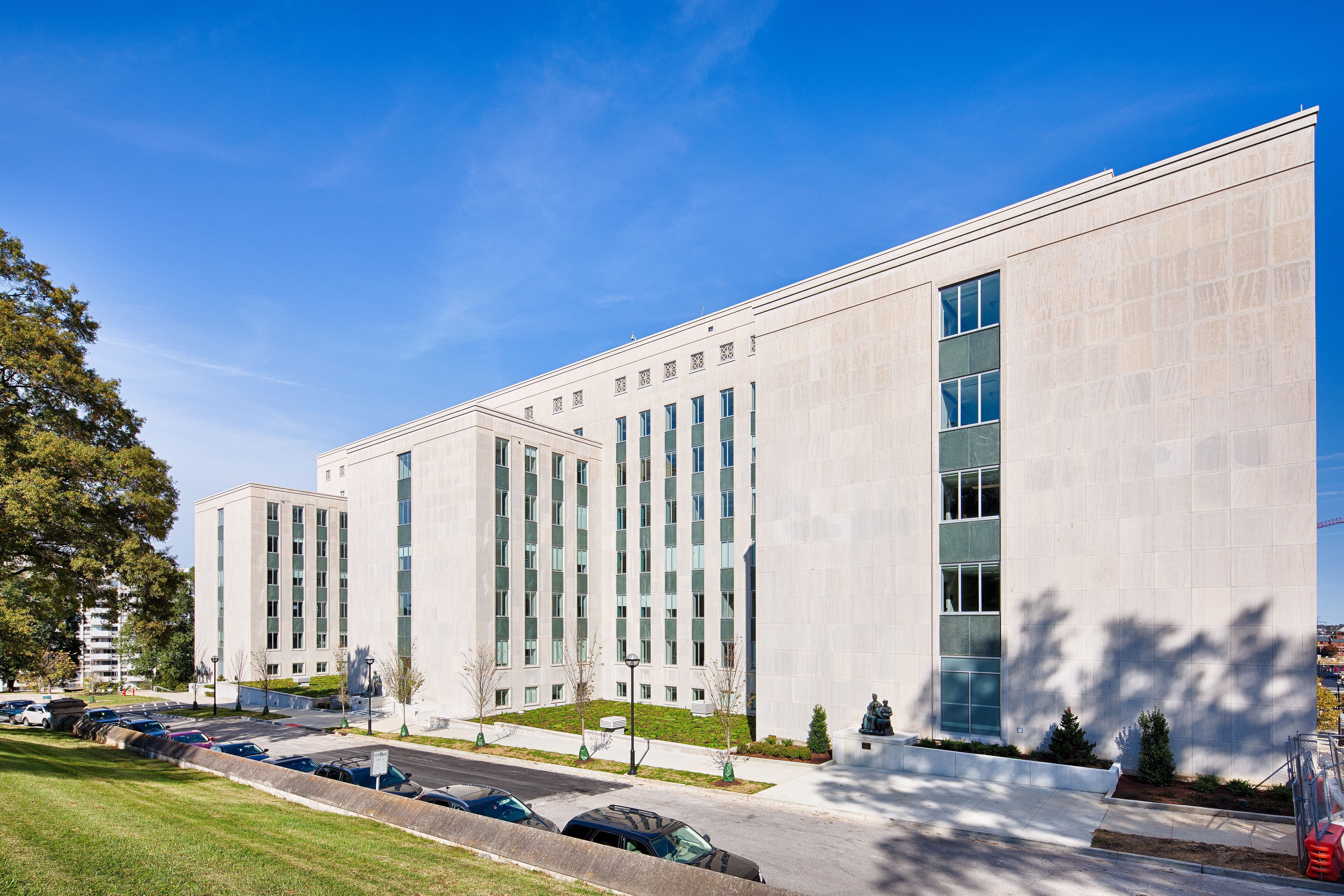 Government Building Exterior with Clear Blue Sky Front view of a large, symmetrical, stone government building with vertical windows and entrance.