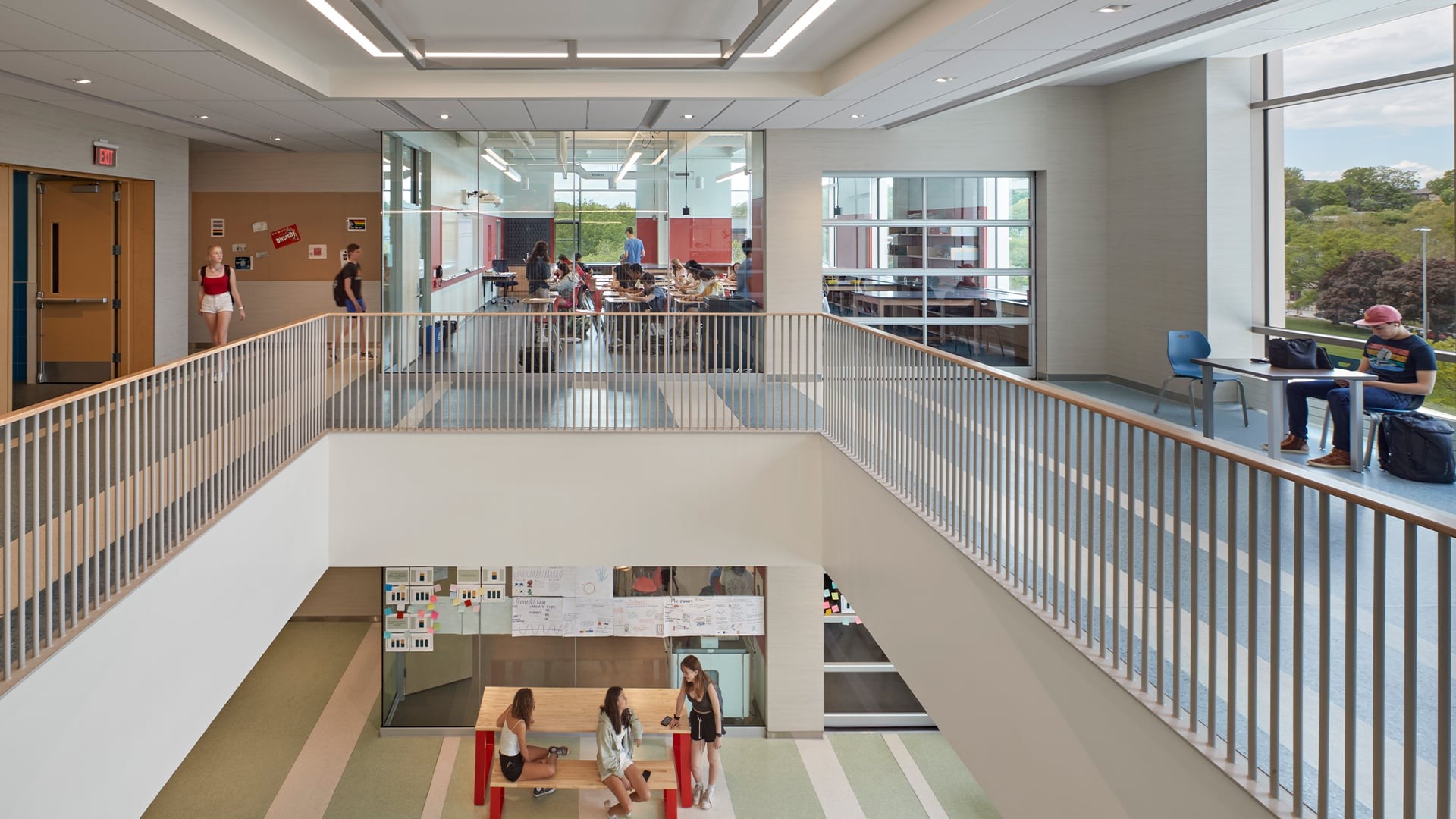Modern school interior with students studying and socializing in bright open spaces.