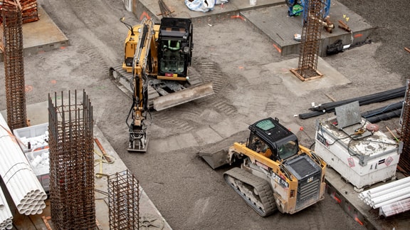 Construction site with excavators and building materials, showcasing active earthwork and development.
