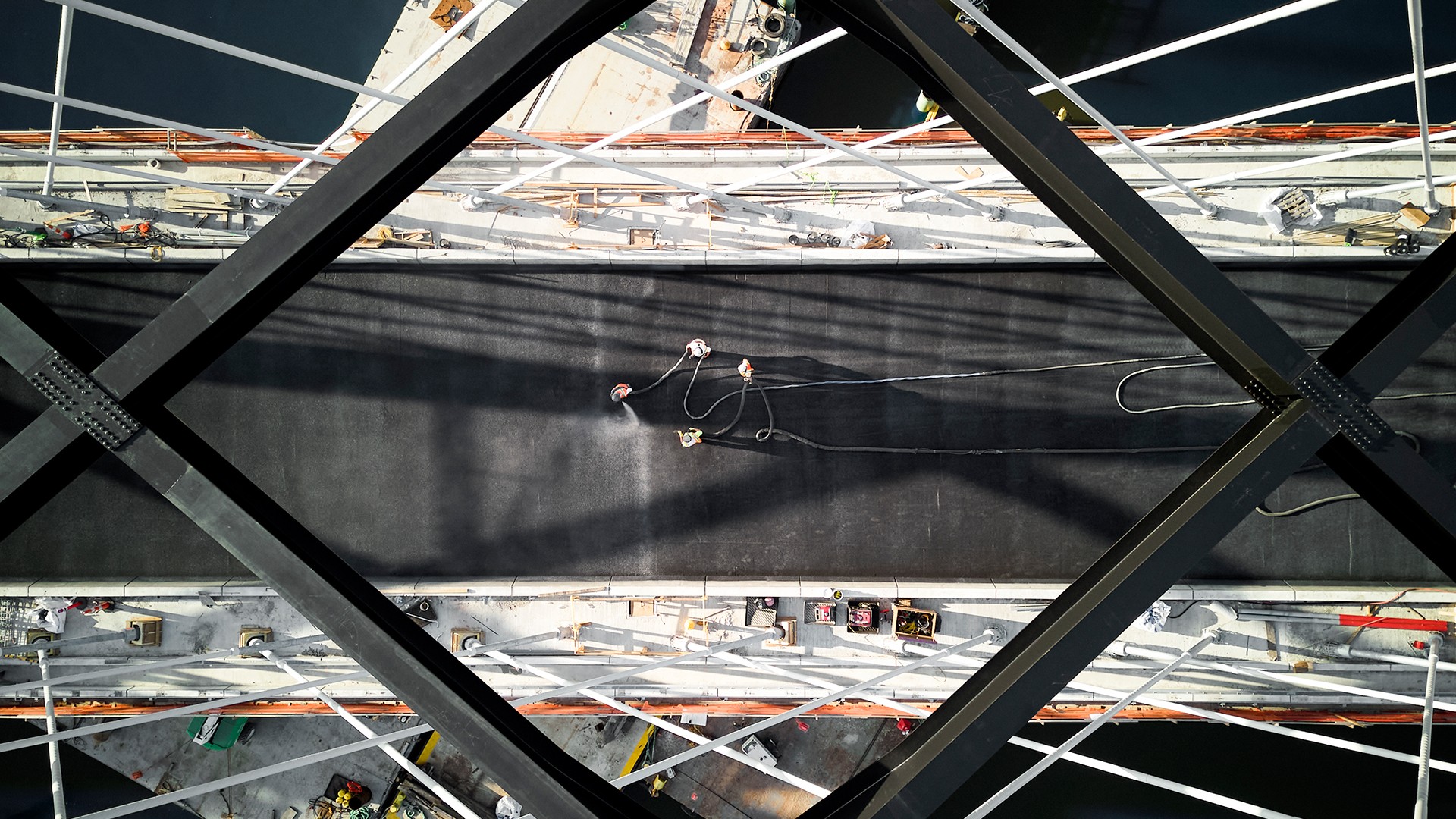 Aerial view of workers performing maintenance on a large industrial bridge structure.