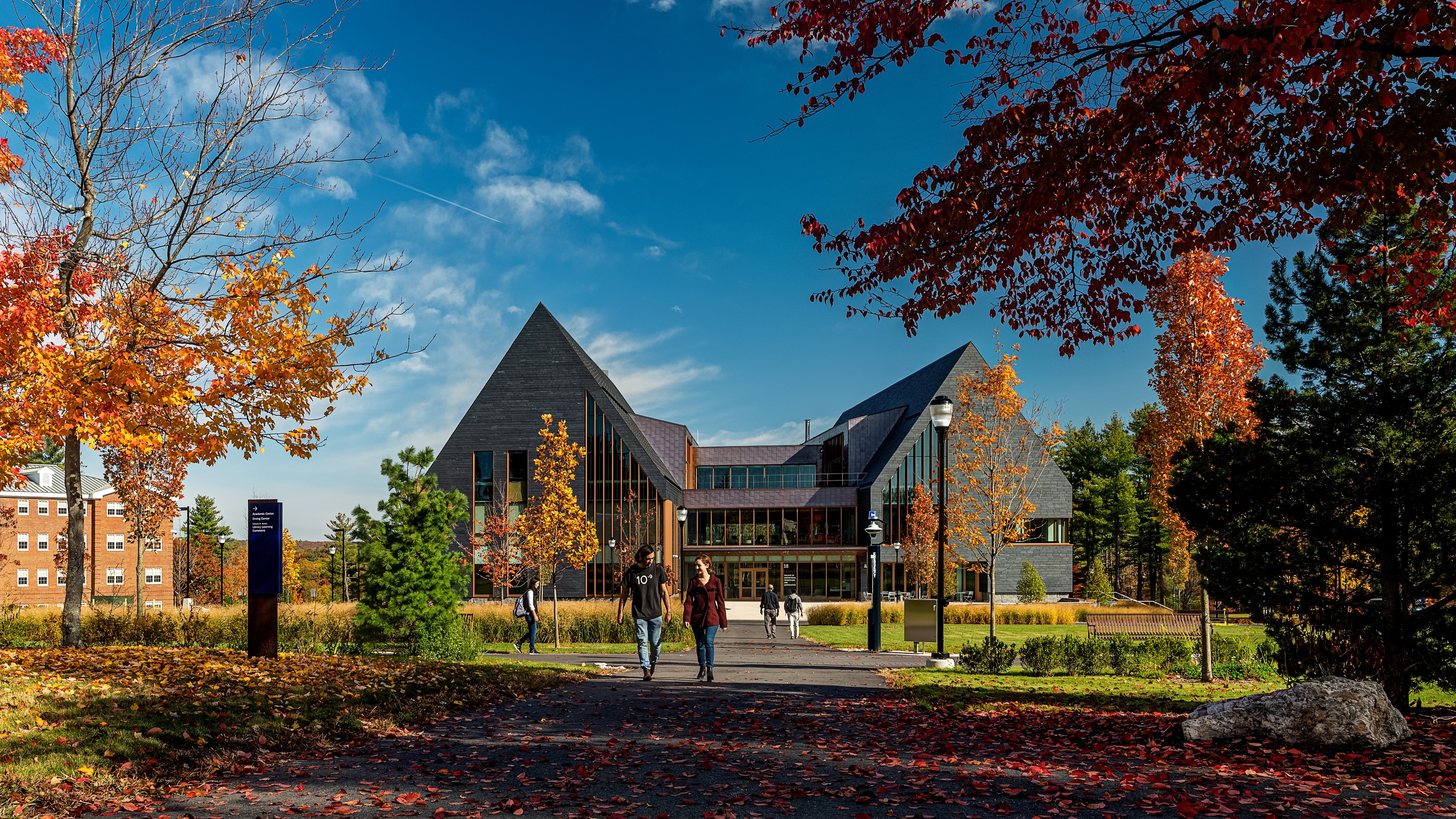 Education lab with Orange Chairs and Advanced Equipment Modern university building with autumn trees and students walking on pathway.