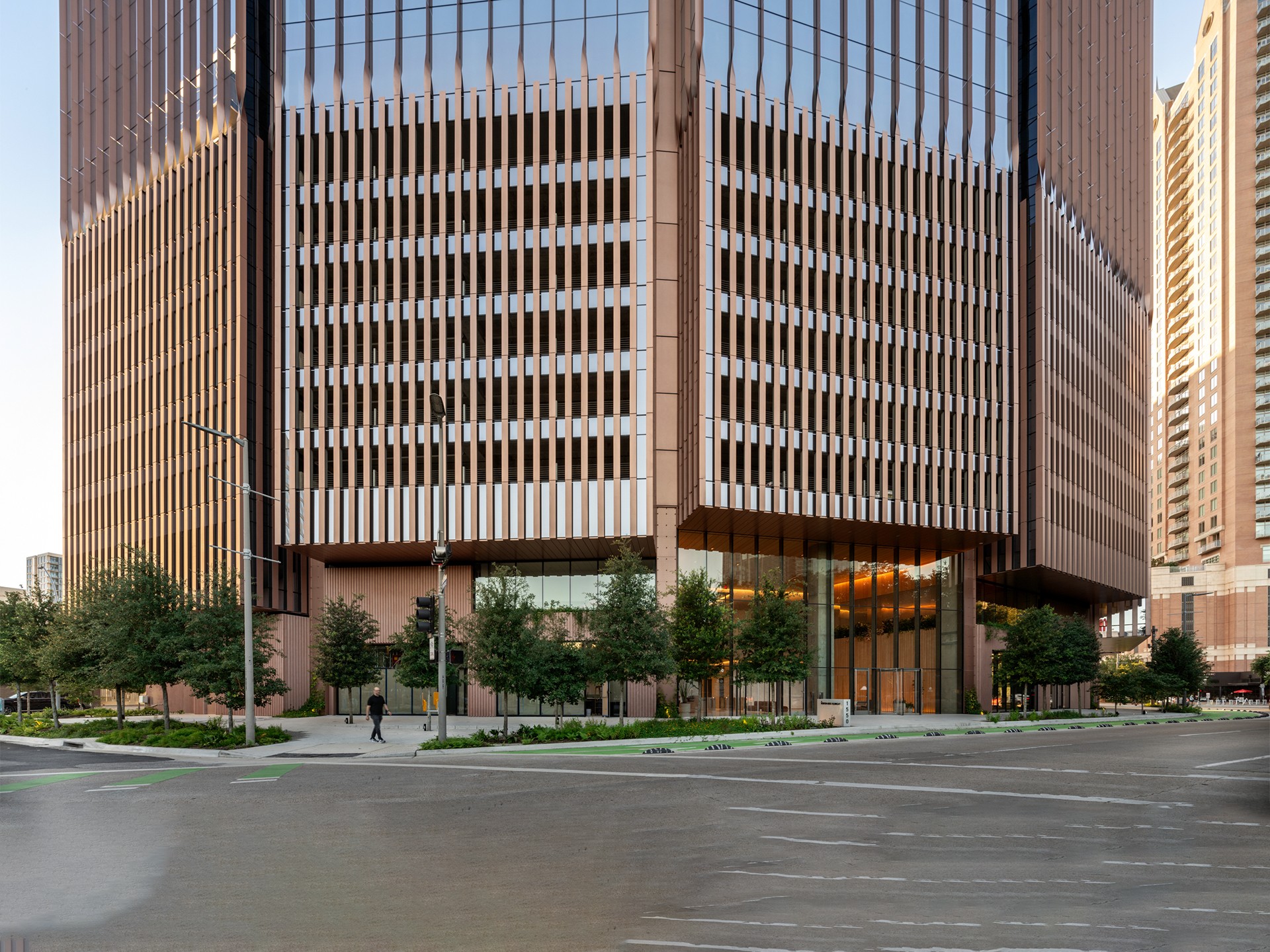 Modern glass office building with trees and street view Modern glass and steel office building with trees and pedestrian at street corner.