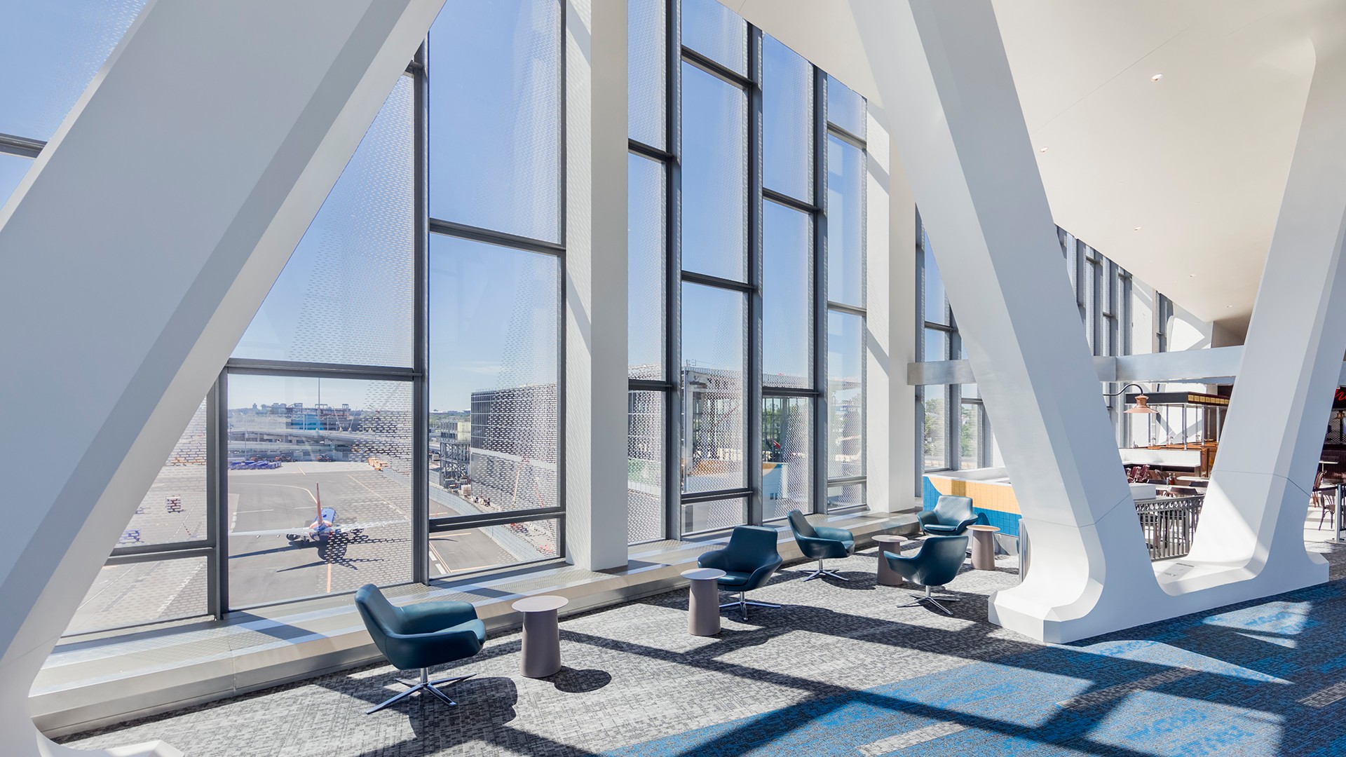 Modern Airport Lounge with Large Windows and Comfortable Seating Modern airport lounge with large windows overlooking the runway and seating area.