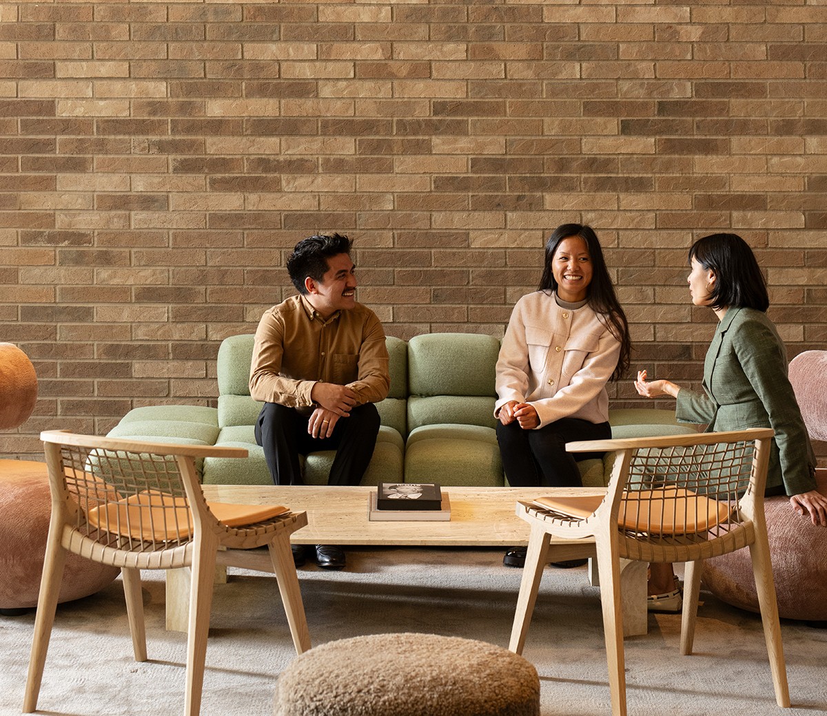 Casual Business Meeting in Modern Office Lounge Area Three people having a discussion on a green sofa in a modern, cozy office space.