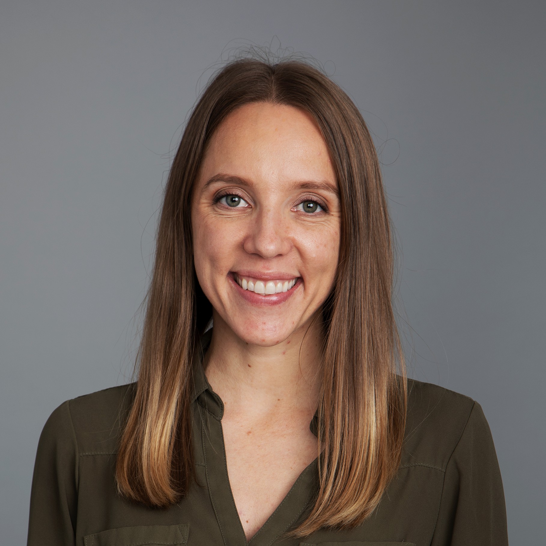 Woman with straight brown hair wearing olive green blouse Portrait of a woman with straight, shoulder-length brown hair wearing an olive green shirt.