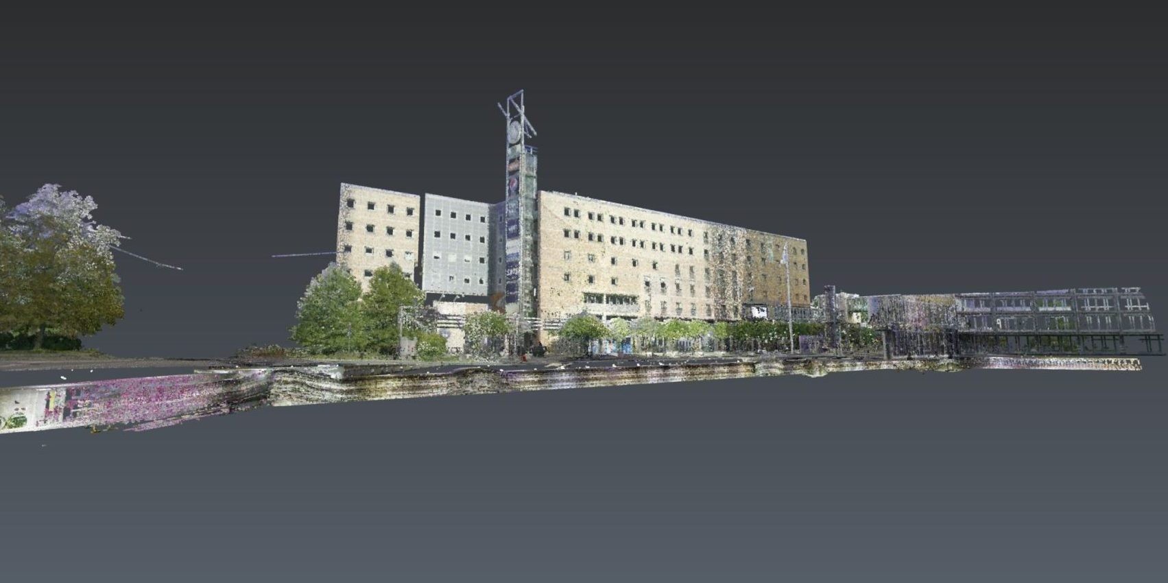 Modern Urban Building with Clock Tower and Greenery View En digital 3D-gjengivelse av en stor bygning med flere etasjer, omgitt av trær og en vannfront.