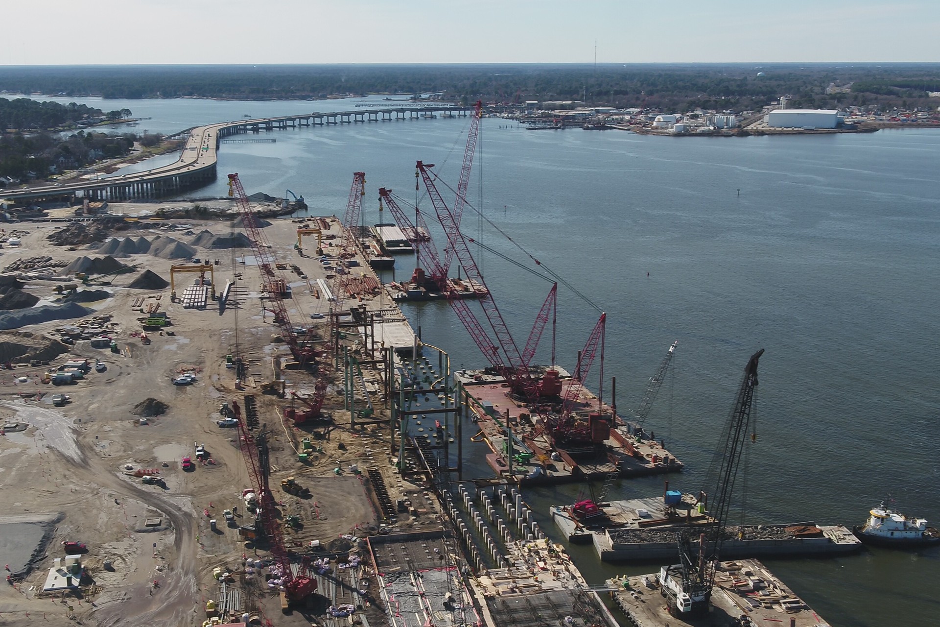 Large-Scale Waterfront Construction with Cranes and Barges Aerial view of a large waterfront construction site with cranes and heavy machinery.