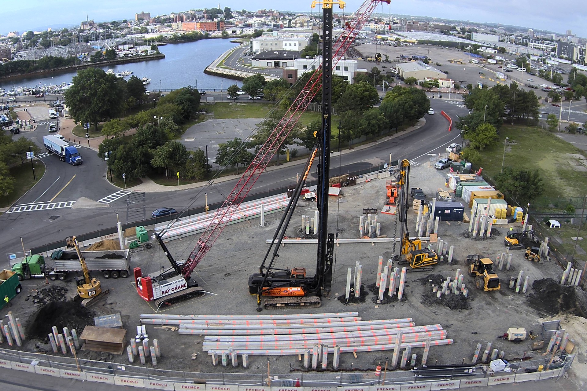 Construction site with cranes and concrete pillars near water Construction site with cranes and concrete pillars near a waterfront city area.