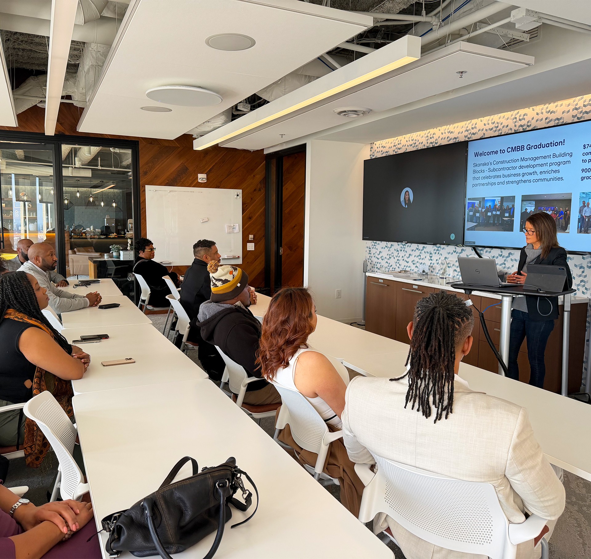 Modern Industrial Facility with Glass Interior Design Group attending a presentation in a modern conference room, with a speaker at the front.