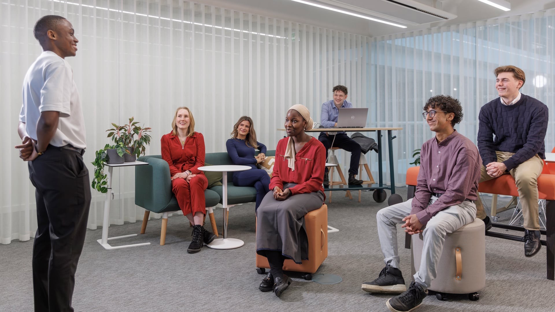 Diverse team in casual office meeting with speaker and attentive colleagues seated.