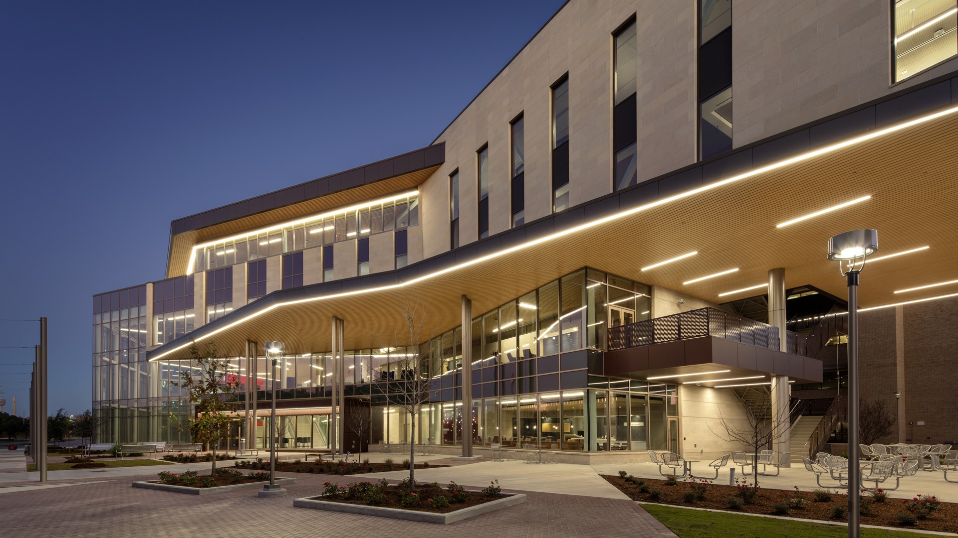 Modern building with large glass windows and illuminated exterior at dusk.