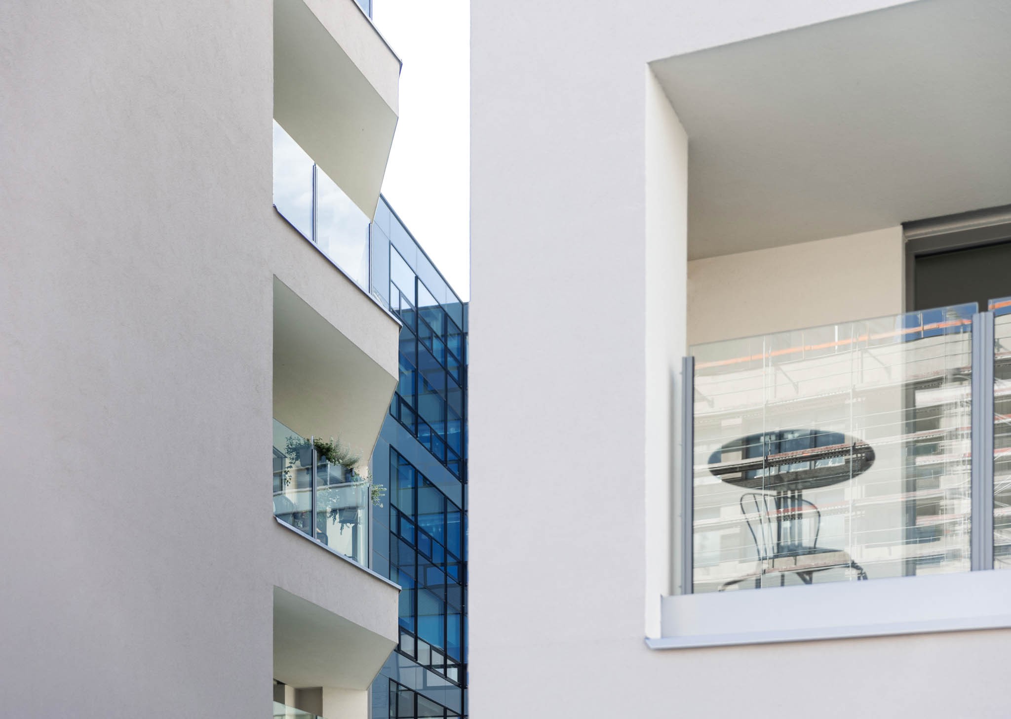 Moderní budovy se skleněnými balkony a odrazy, představující současnou městskou architekturu.