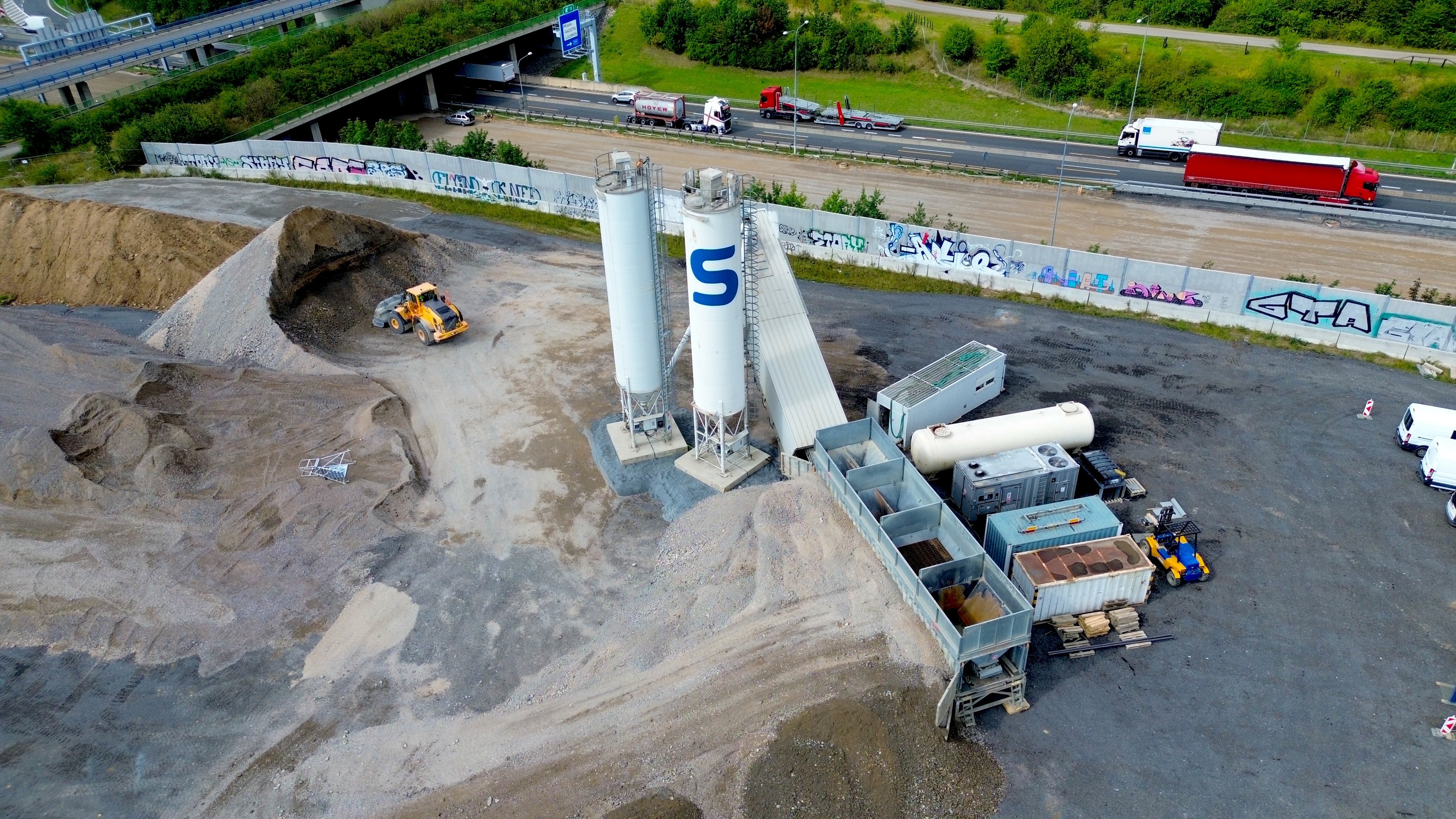 Mobilní betonárna u D0 Letecký pohled na mobilní betonárnu s mechanizací a nákladními auty.
