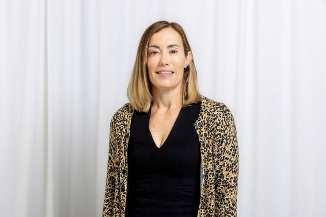 Stylish Leopard Print Cardigan with Black Dress Outfit Woman in black dress and leopard print cardigan standing against a white curtain background.