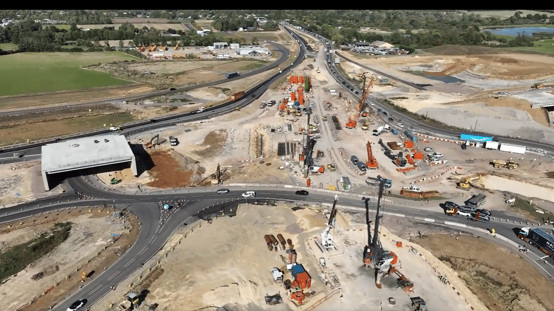 Aerial view of a large highway construction site with heavy machinery and traffic.