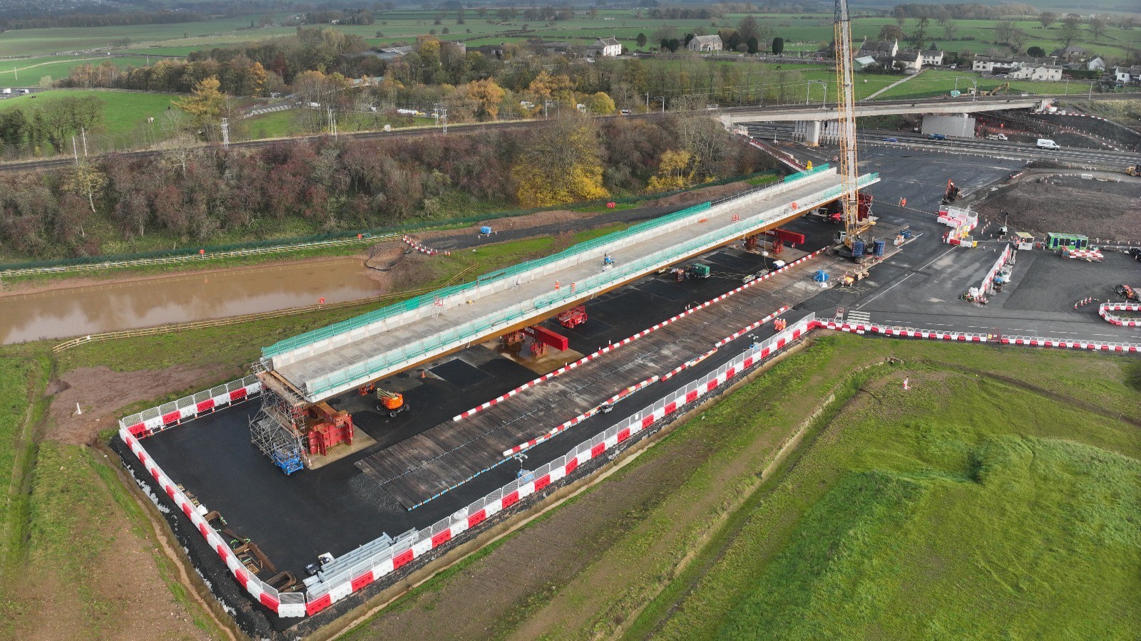 Aerial view of a bridge under construction over a river in a rural area.