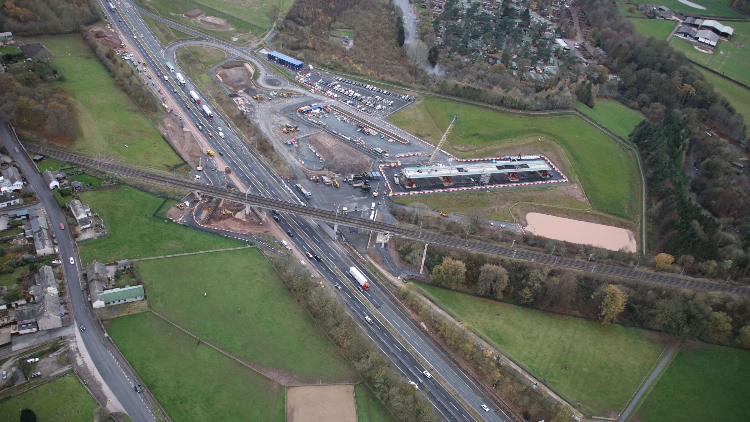 Aerial view of a highway interchange with multiple lanes, vehicles, and surrounding greenery.
